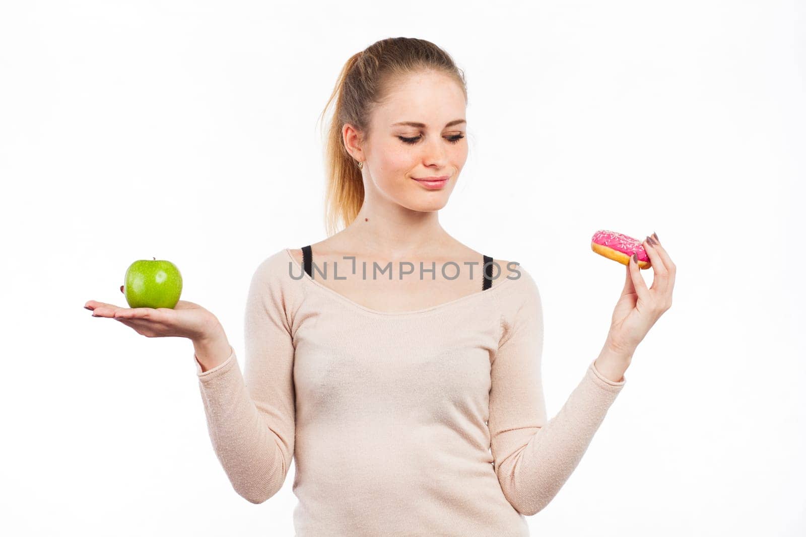 Portrait of a beautiful girl with a green apple and a donut, isolated on white