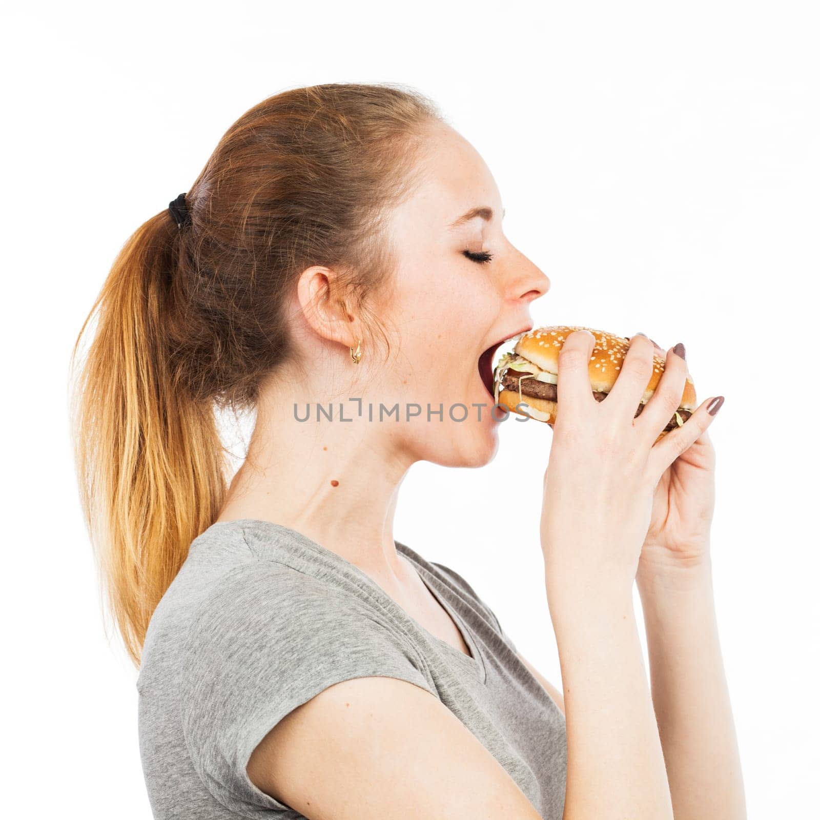 Portrait of a cute young woman eating a burger, isolated on white