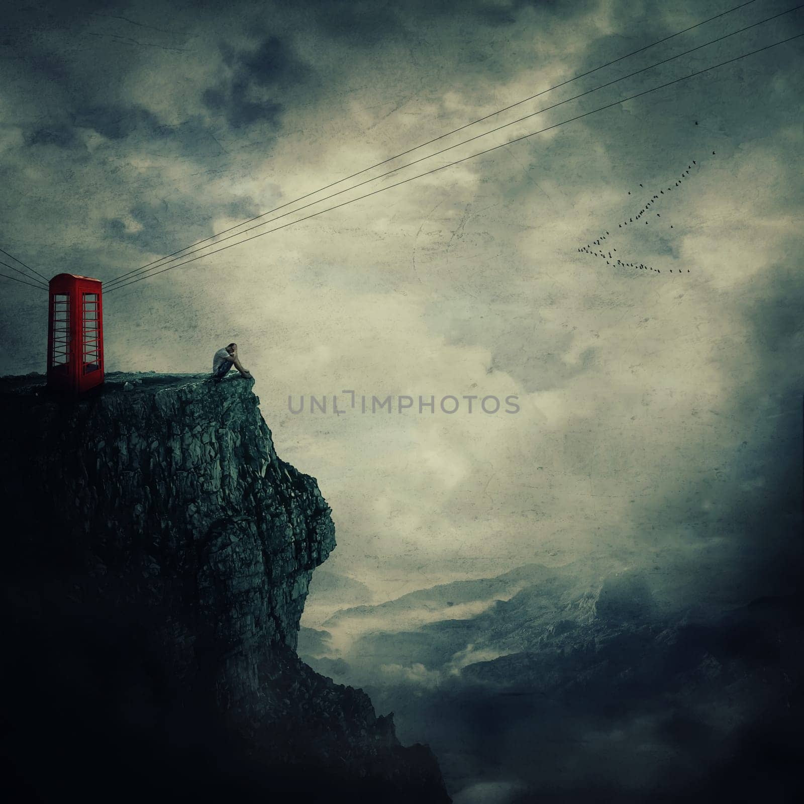 Surreal view as a sad, young man, standing on the edge of a cliff near a red telephone box, waiting someone to call him.