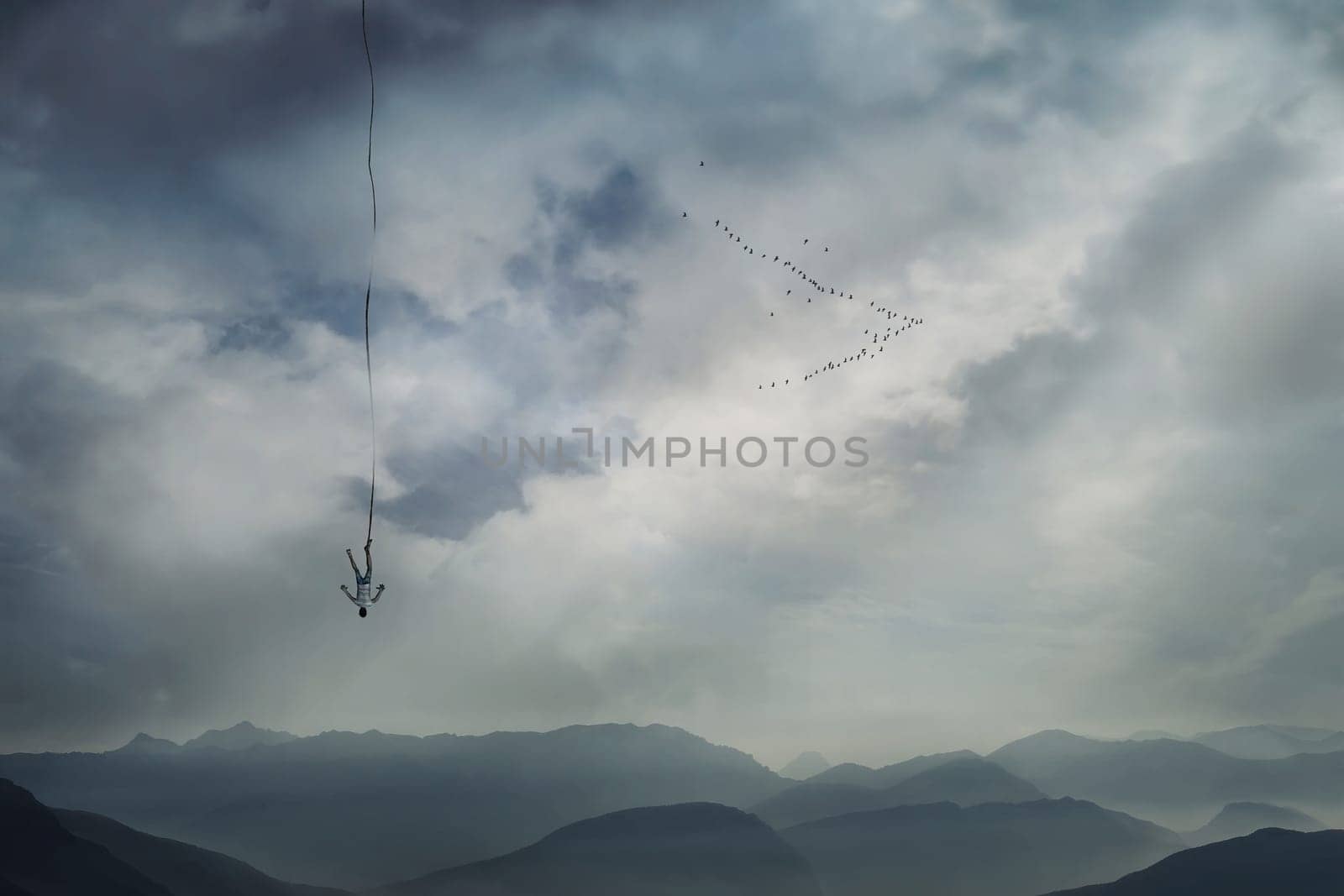 Young man falling from the sky with a rope tied to his leg as safety insurance. Base jump, mysterious crash, life risk and hard determination concept.