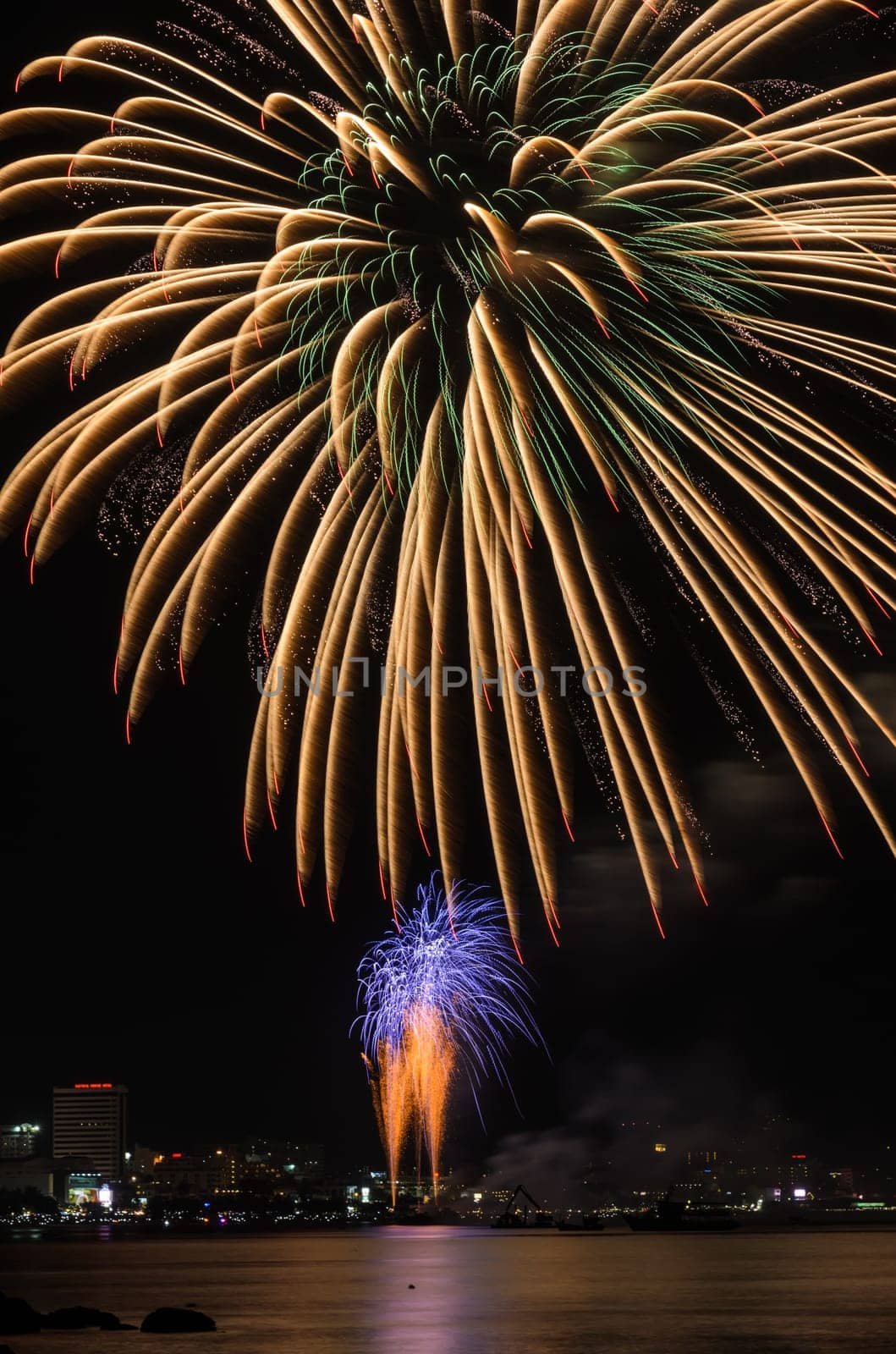 Big yellow firework on the sky at Pattaya coast with cityscape background, Thailand
