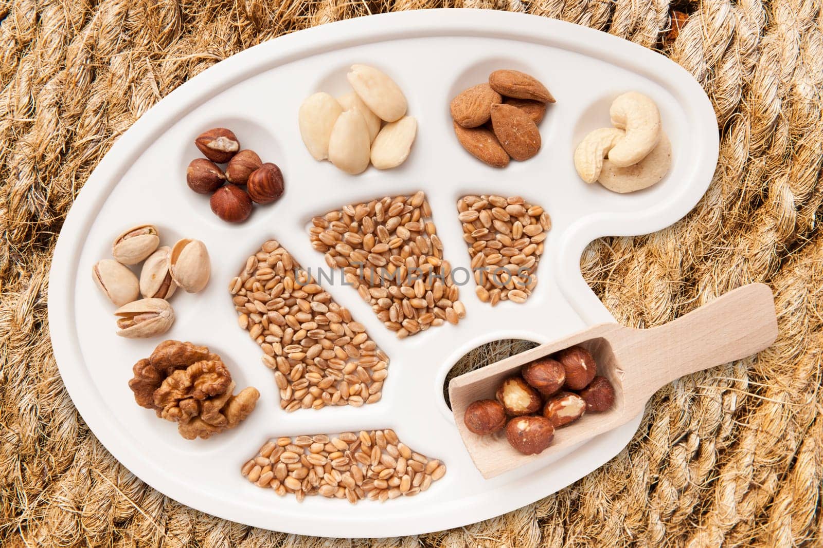 Various nuts,almonds and grains on white painter's pallet freed on sisal braid.