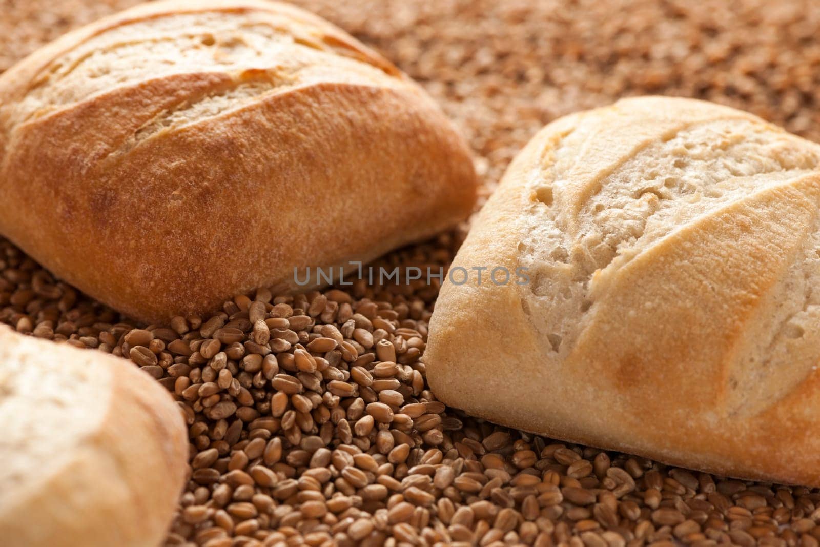 Two square rolls softly lit on spelt grains.