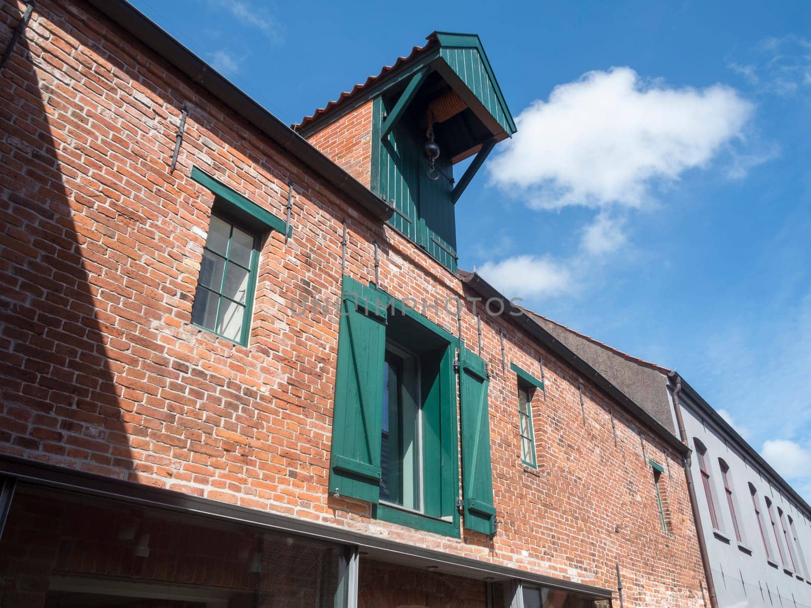 Brick façade of an old warehouse with crane in the city north before building sky with white cloud.