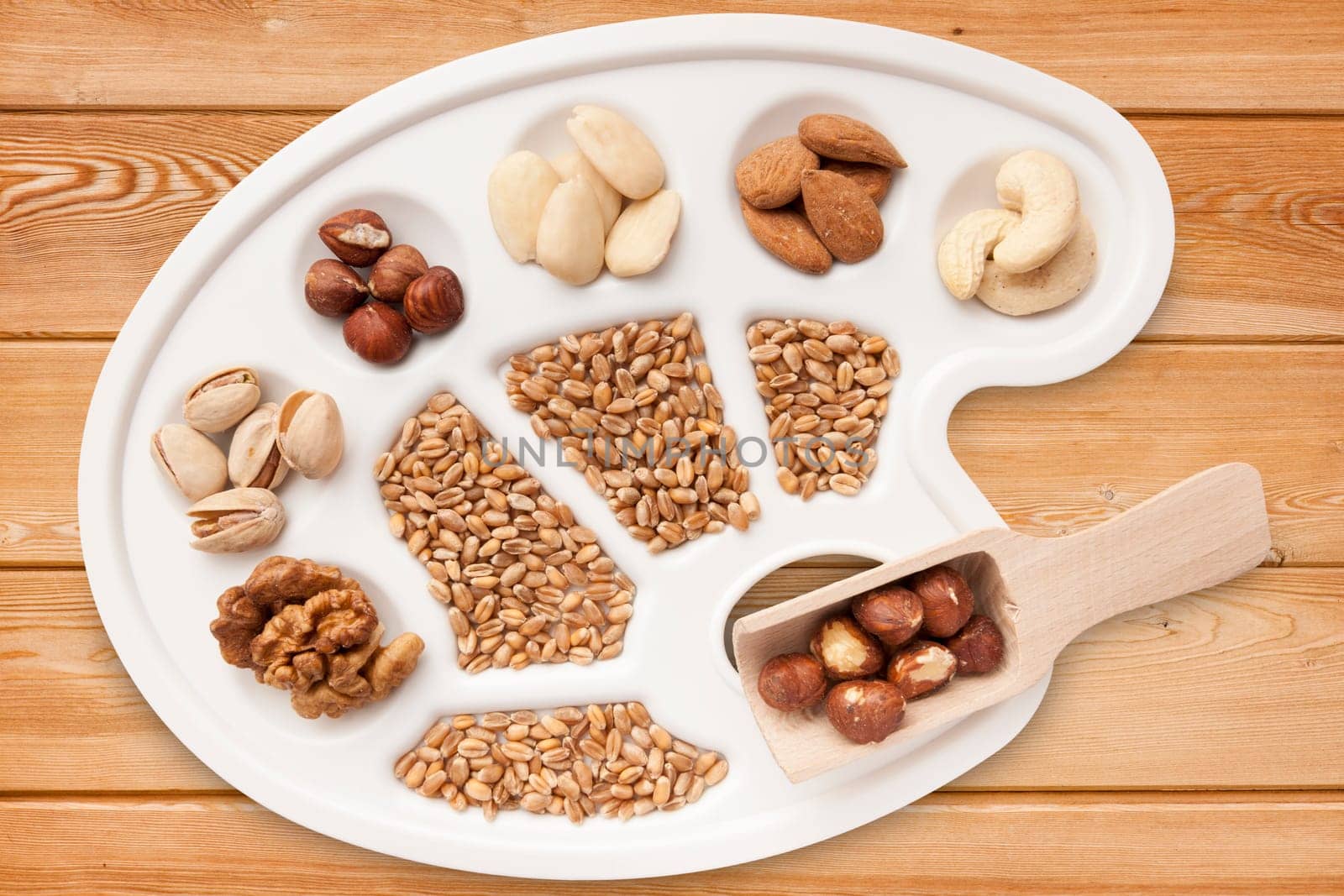 Various nuts,almonds and grains on white painter's pallet exposed on spruce boards.