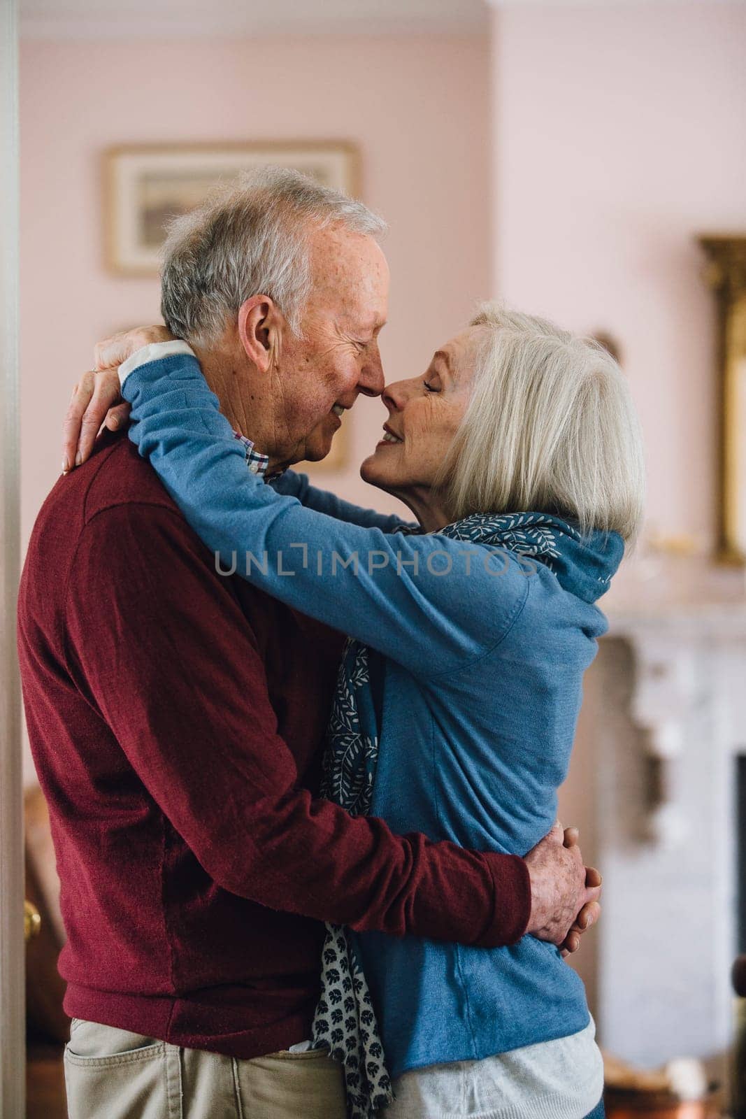 Senior couple are kissing on the lips in their home.
