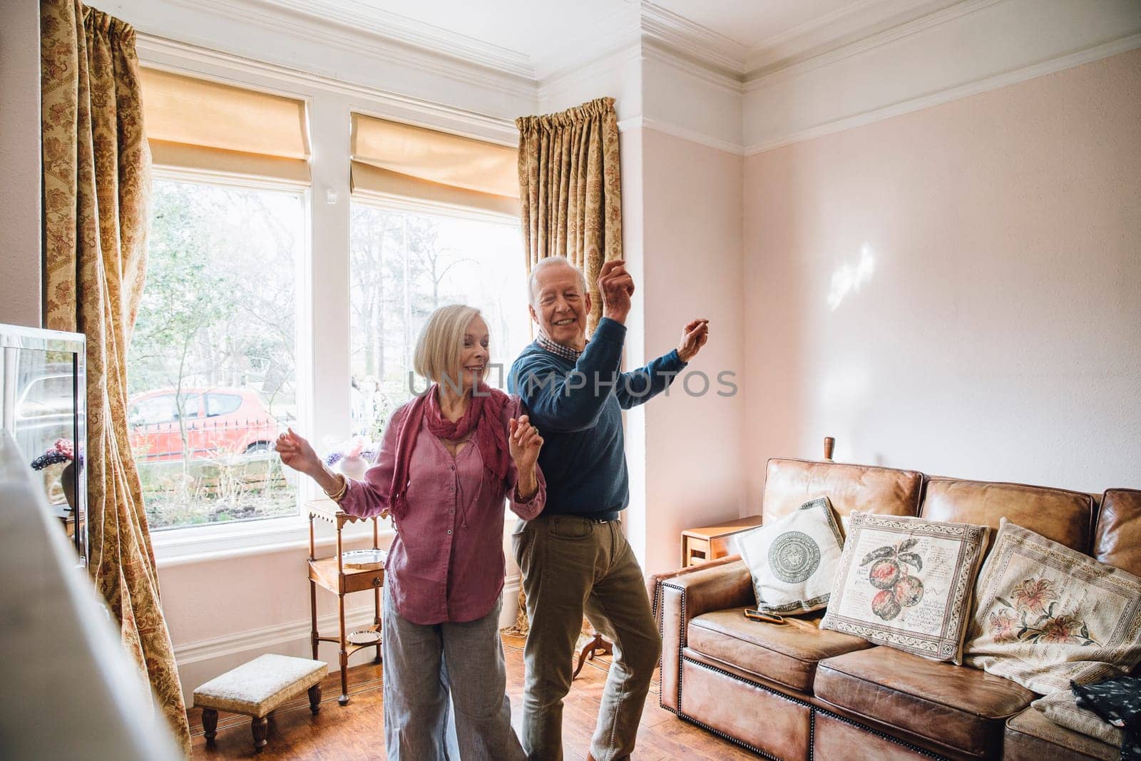 Senior couple are enjoying a dance in the living room of their home.