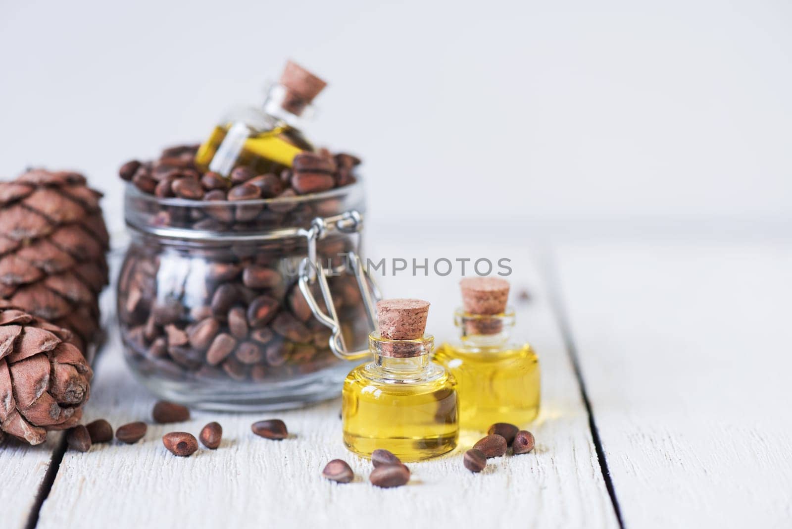 The cedar oil in a glass bottle on a white wooden background. Source of essential fatty acids for healthy nutrition