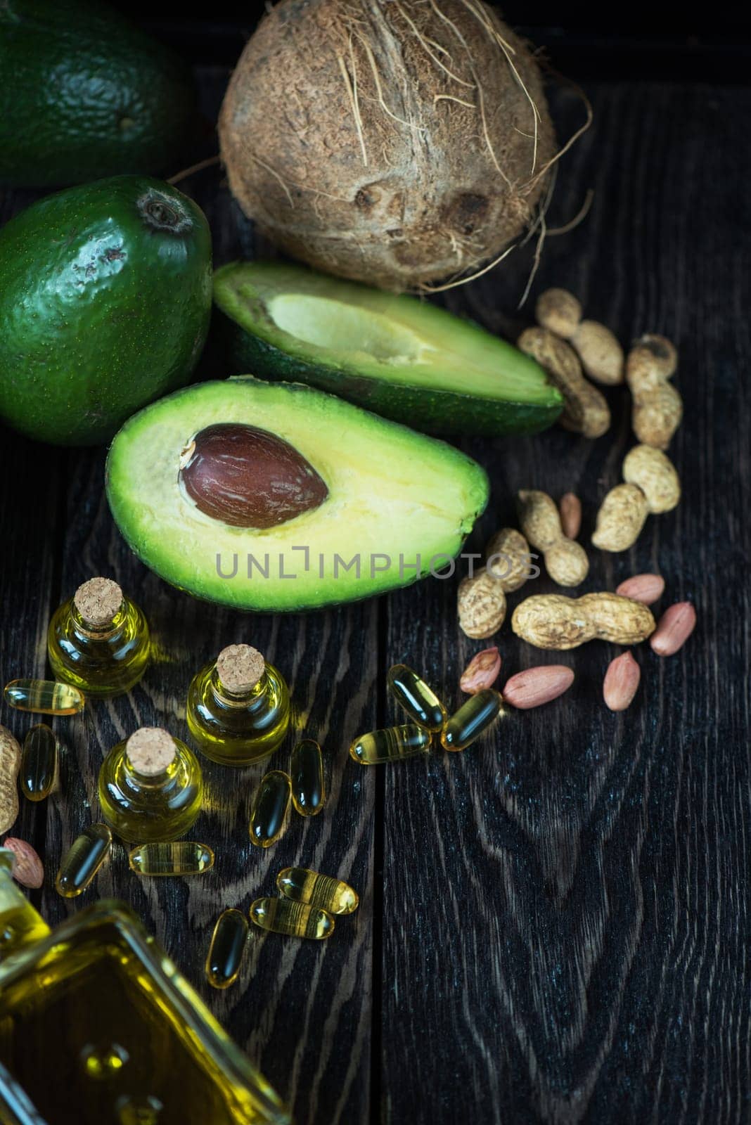 Oil of avocado with fish oil pills and peanut - source of omega 3 on a dark wooden background