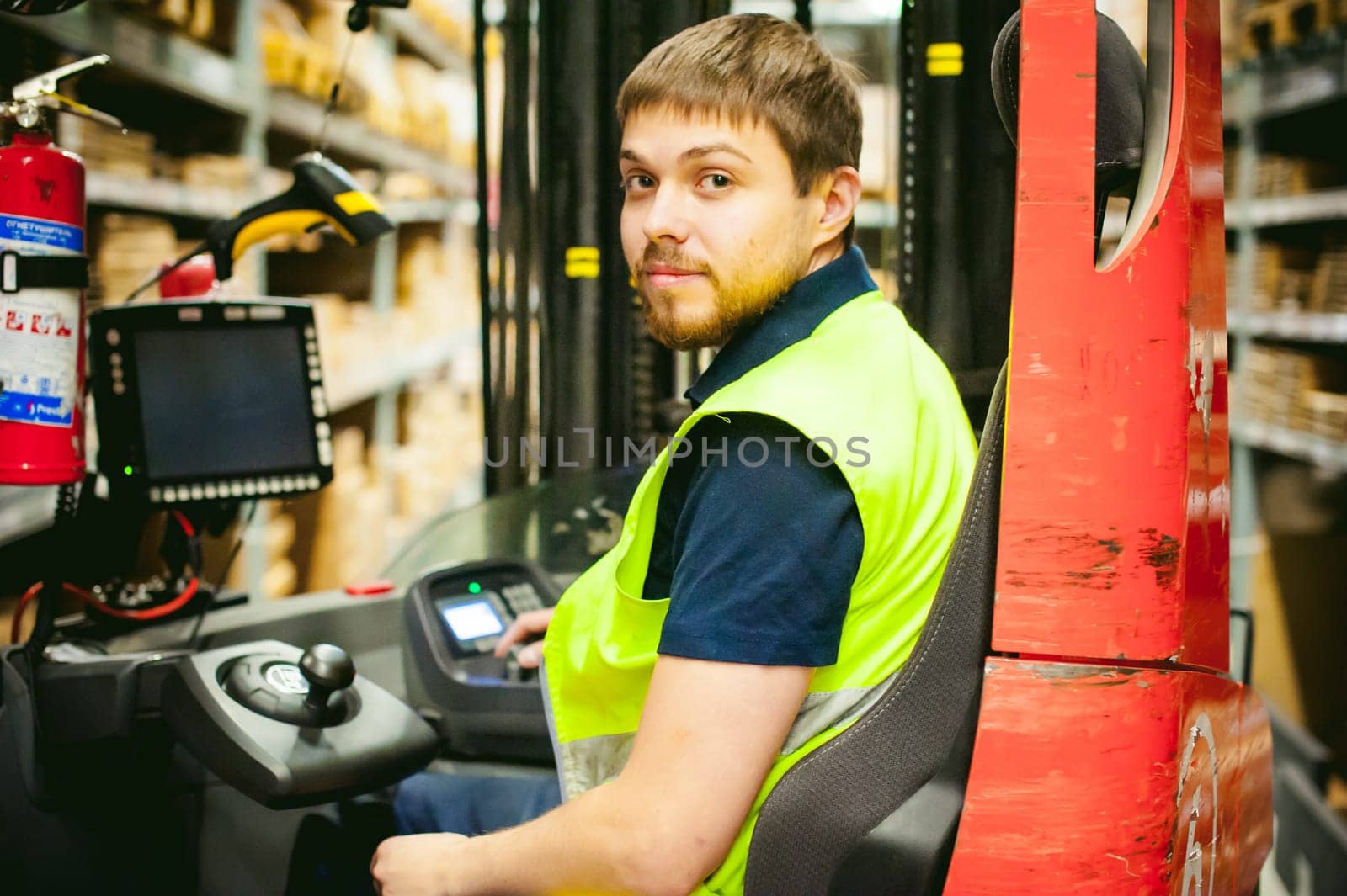 young man in working clothes, driver Reachtruck busy working on the logistics warehouse store