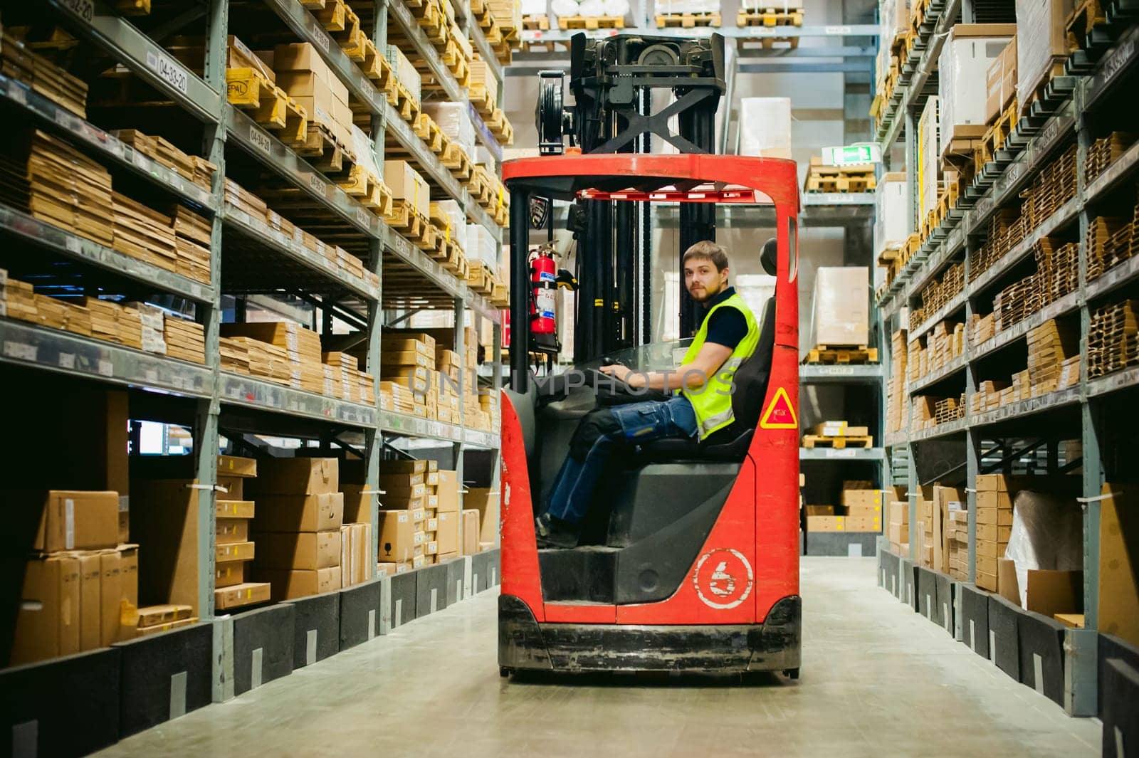 young man in working clothes, driver Reachtruck busy working on the logistics warehouse store