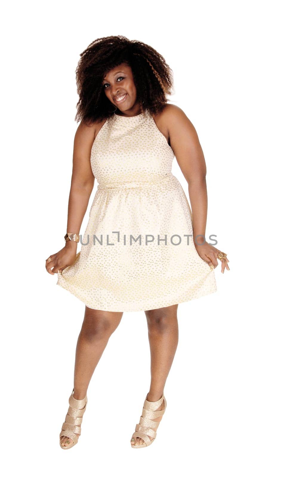 A smiling image of a African American women in a beige dress and messy.hair standing isolated for white background..