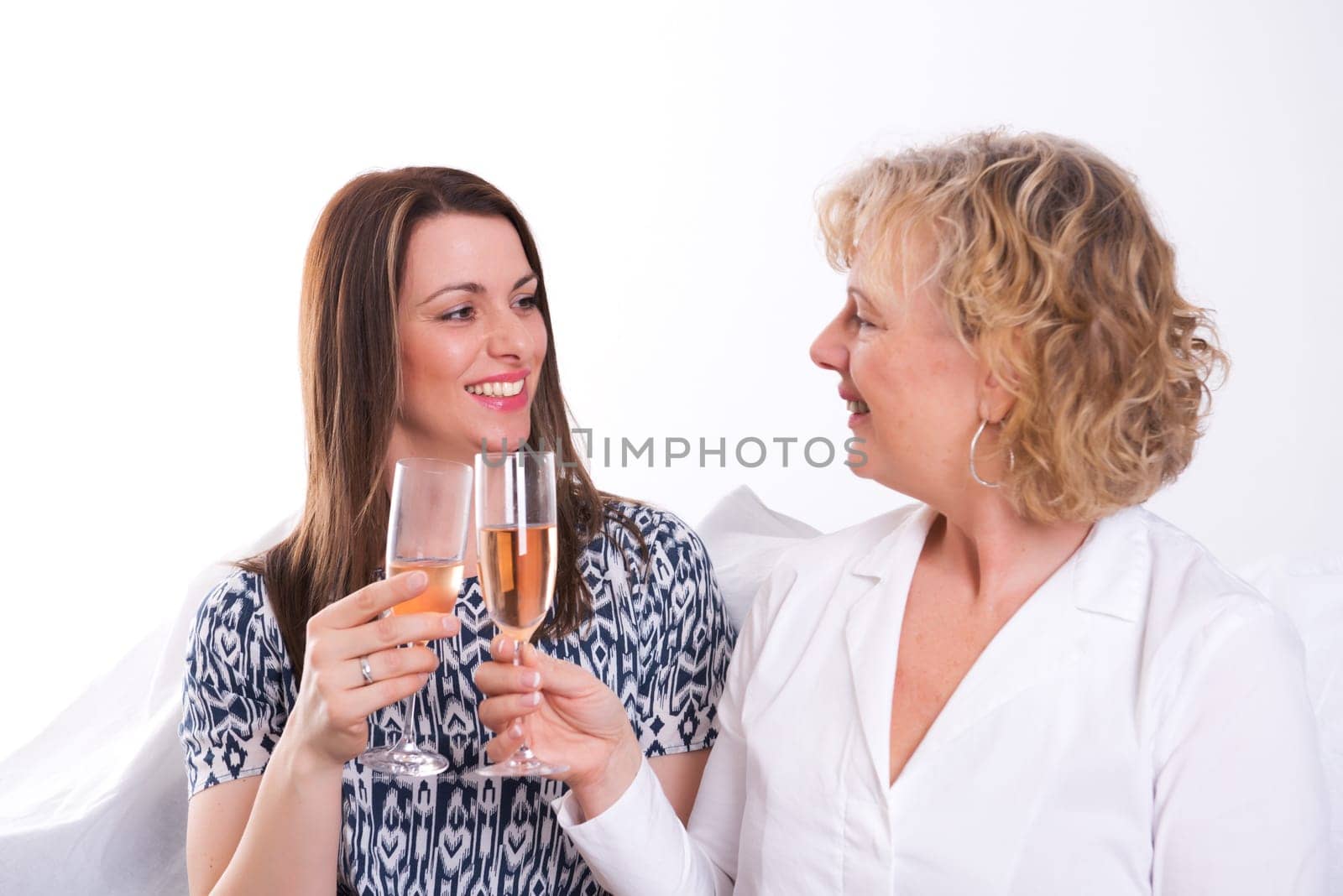 young woman and her mother drinking champagne in front of white background