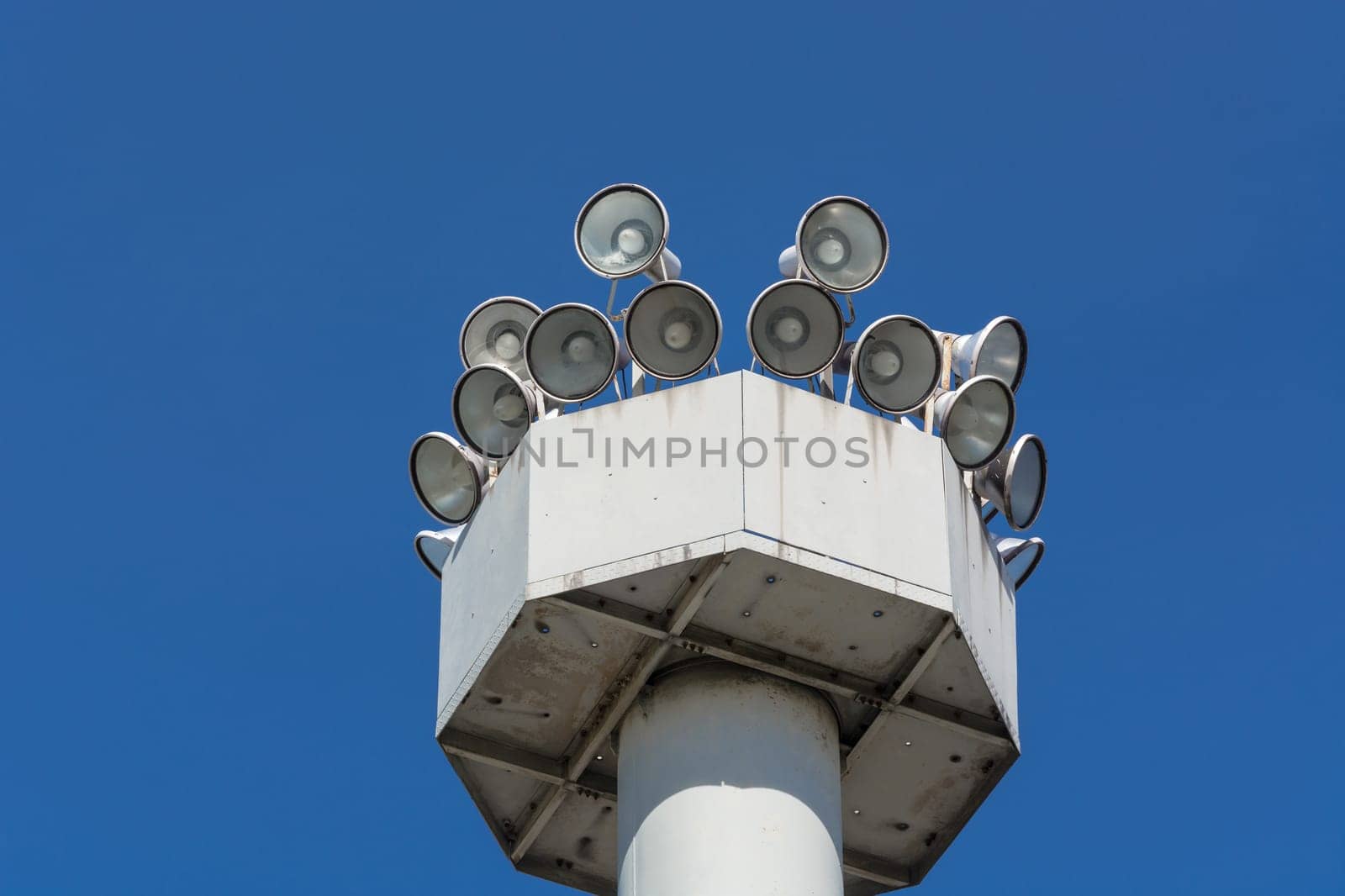 Many speakers on high tower against a clear sky background..