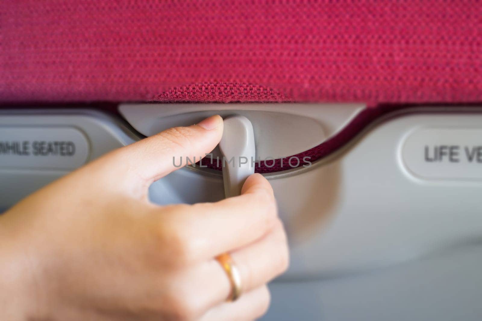 Hand On Hidden Table Of Airplane Seat, stock photo
