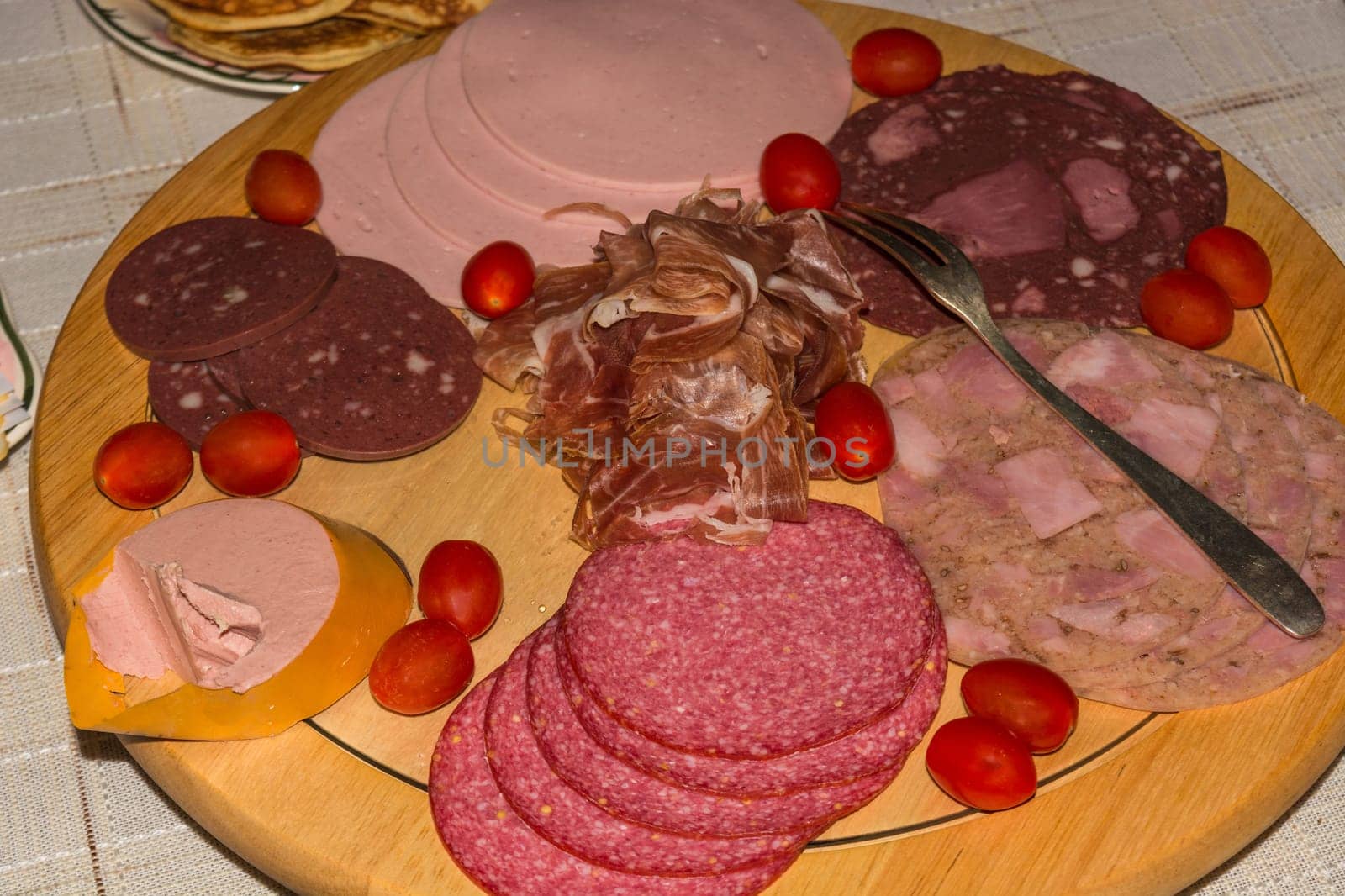 Different types of sausage on a round wooden board..
