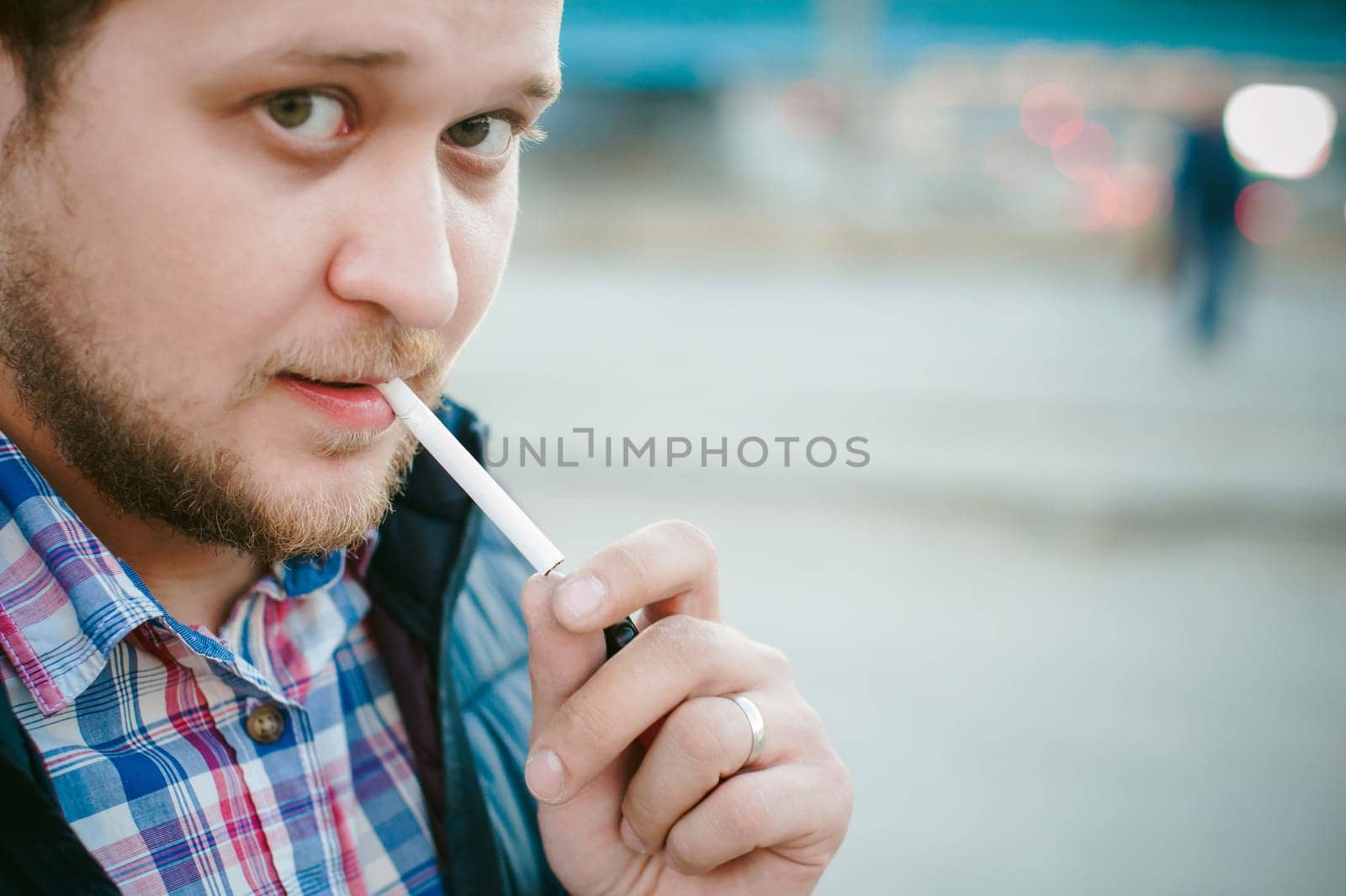 cigarette smoking. a man with a beard smokes a cigarette on the street in a public place.