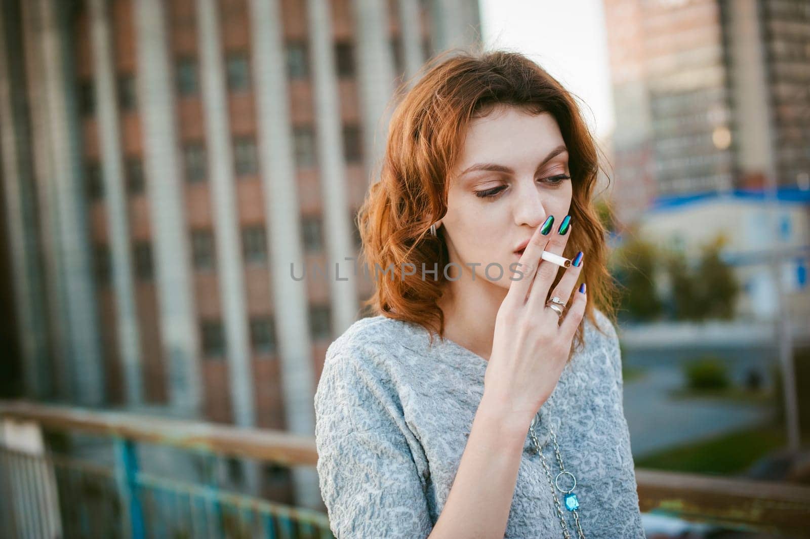 girl with a cigarette. young beautiful woman smokes a cigarette in the street
