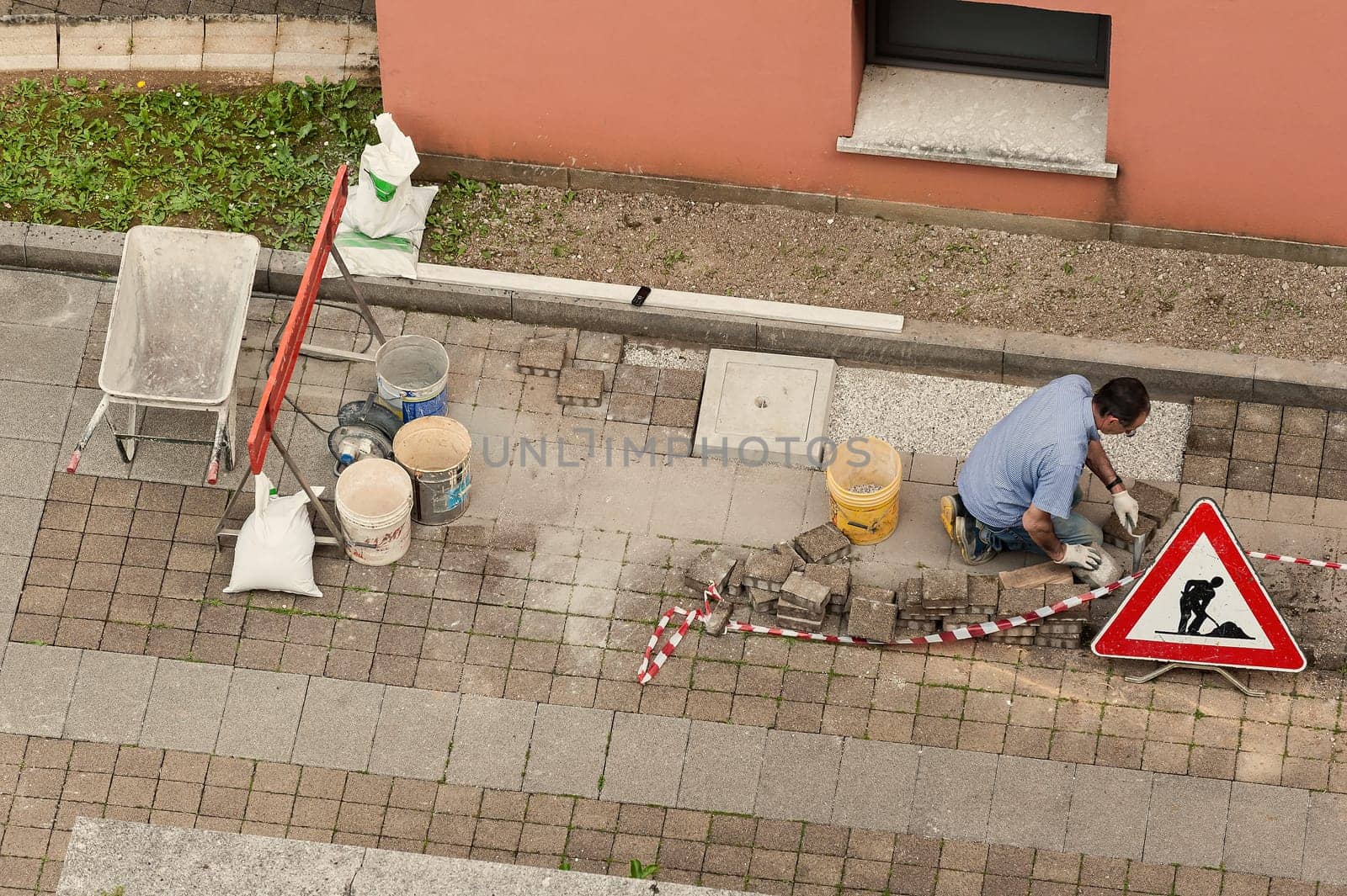 Bricklayer at work laying stone blocks of pavement.