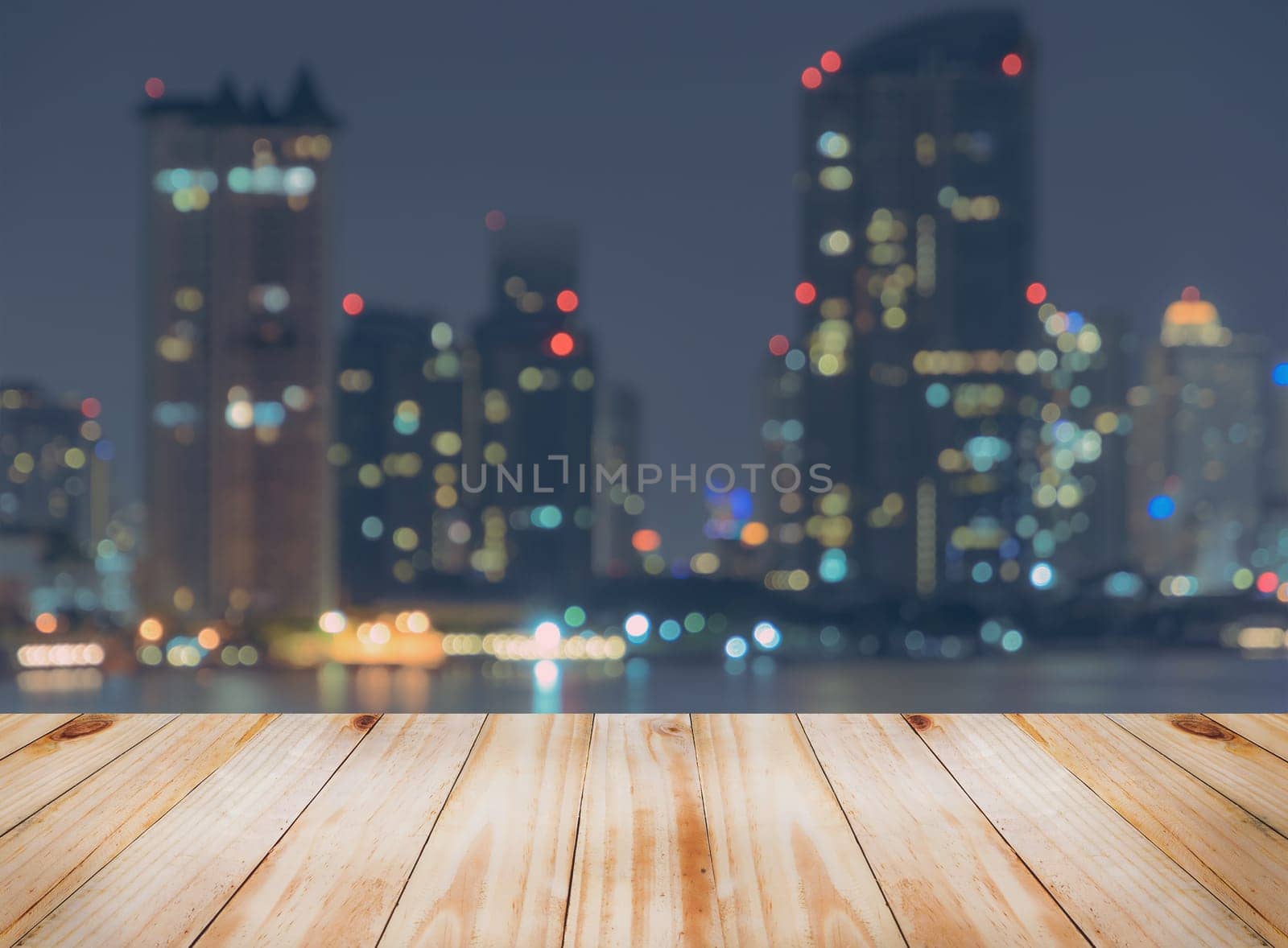 Empty wooden table top with blurred city skyline background at night, can be used for montage or display your products