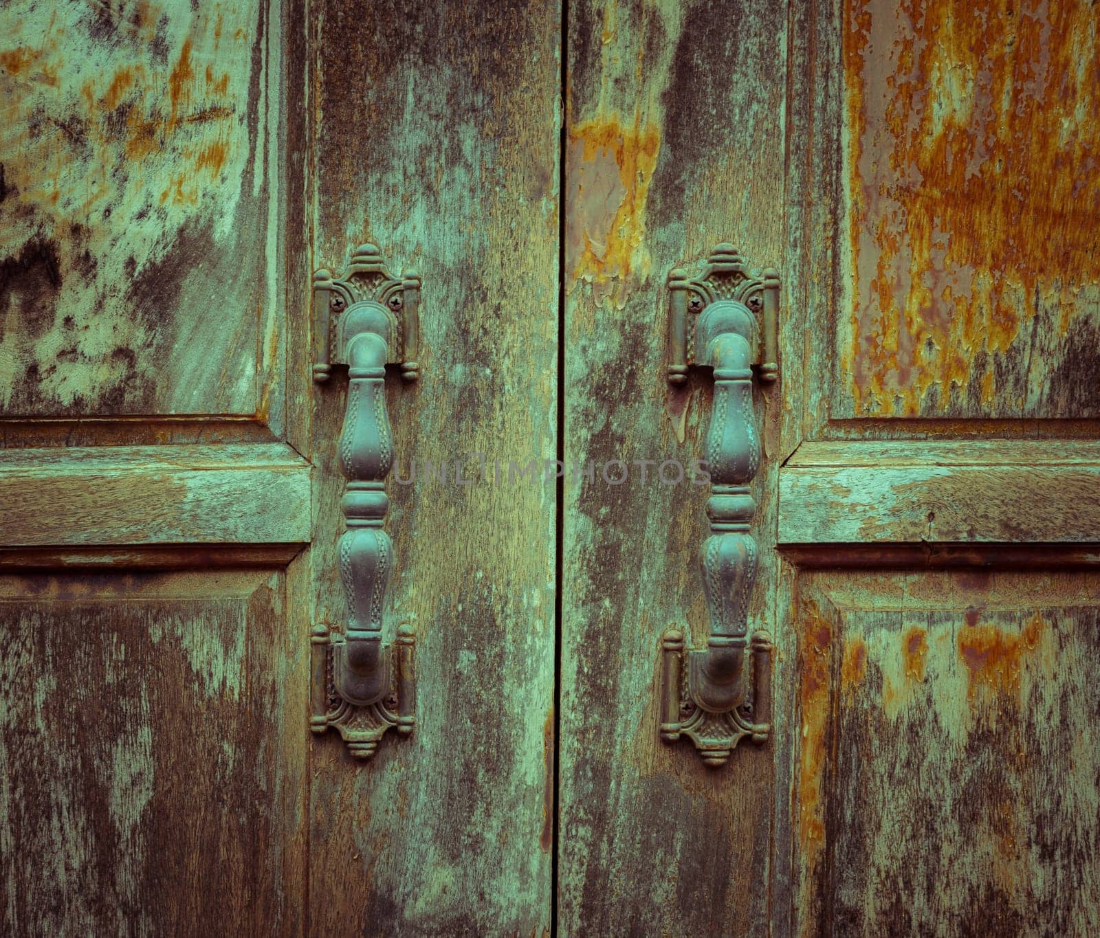 Grunge wooden door with metal handles. Vintage filter effect image.