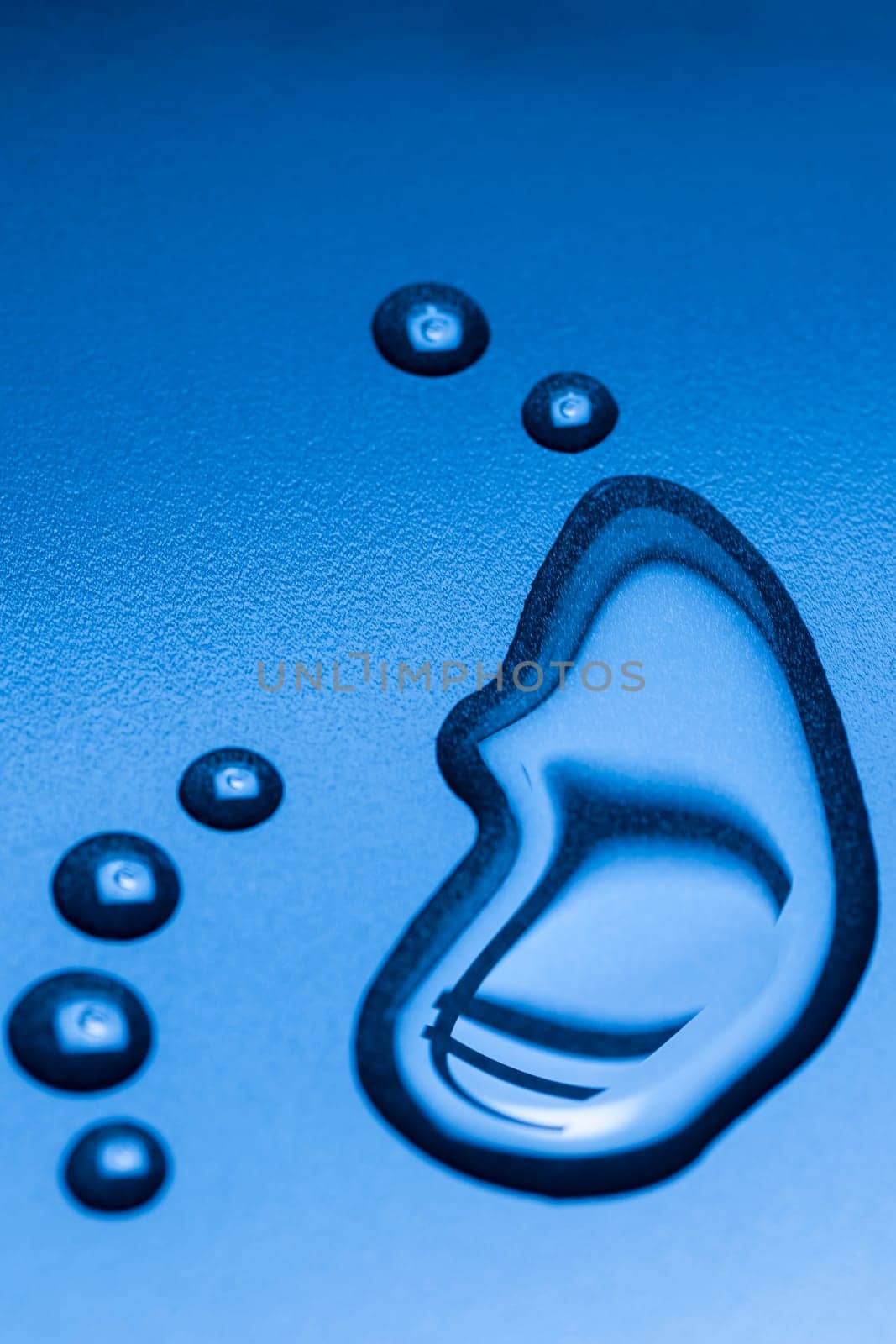 A running large liquid drop and several smaller drops with mirrored EURO symbol on a blue background.