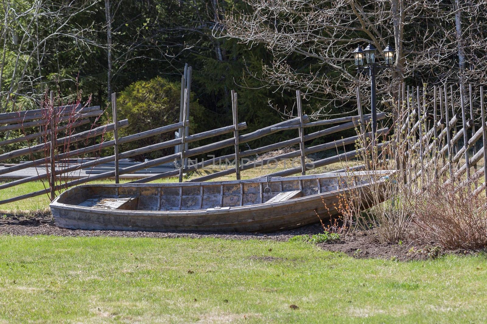 Rowboat in Garden in front of wooden fence.