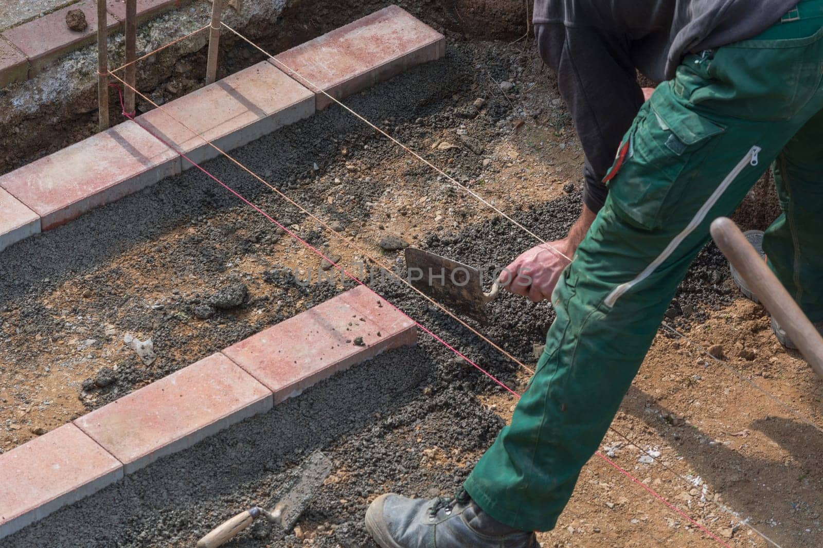Workers in the pre-travel for laying paving stones and Ziegelsteine.Im background various tools.