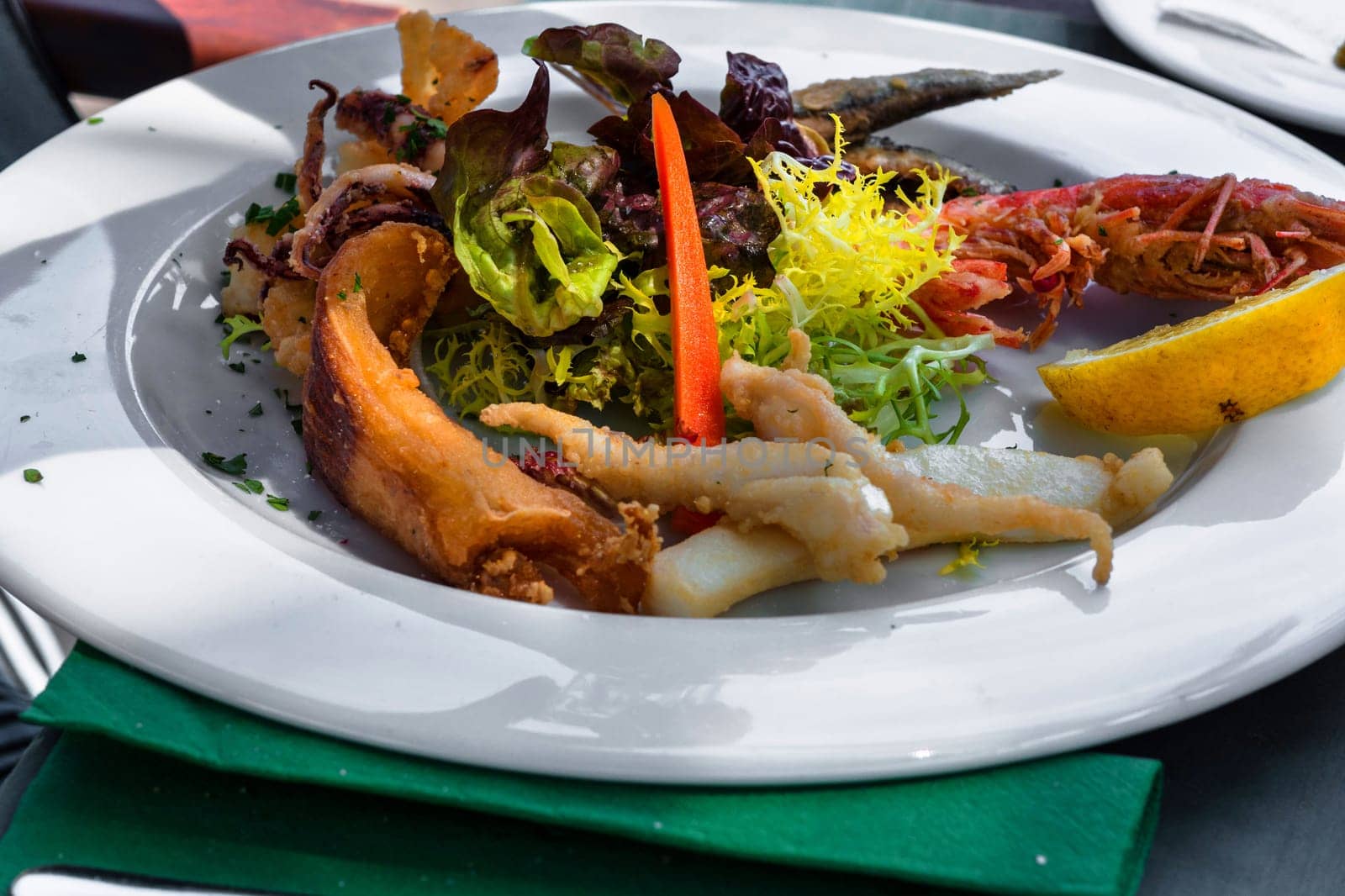 Close-up of various grilled fish varieties on a white plate in the restaurant..