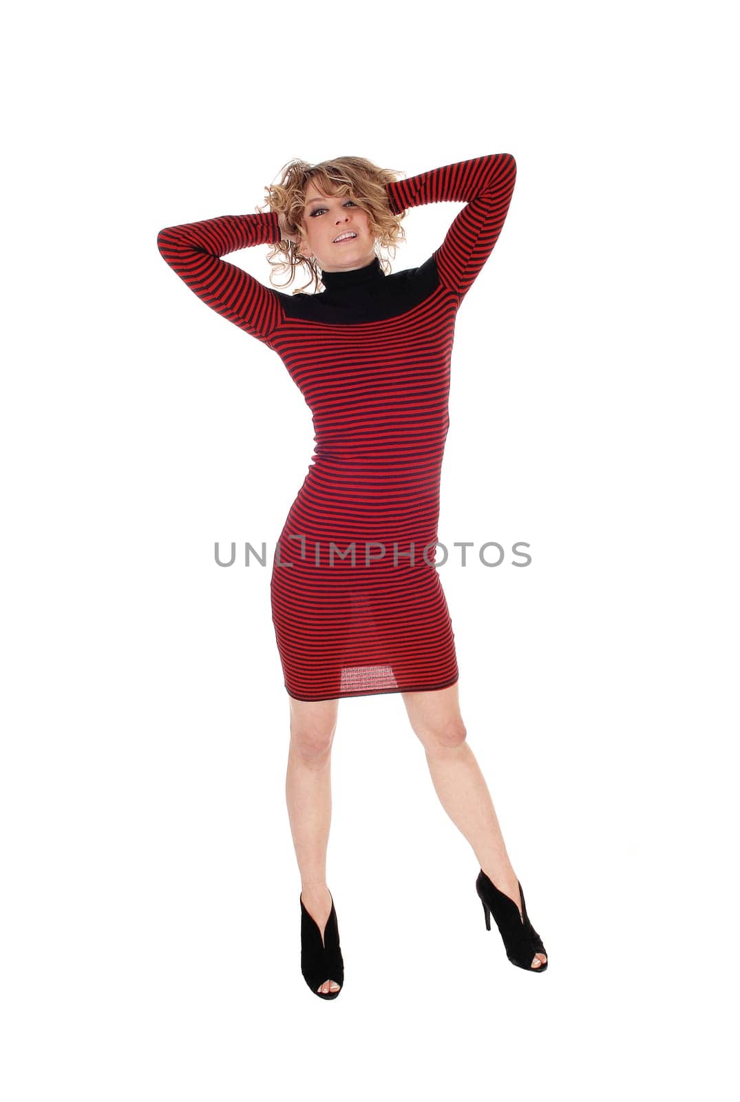 A young Caucasian woman in a  striped red and black dress standing.with her hands behind her head, isolated for white background..