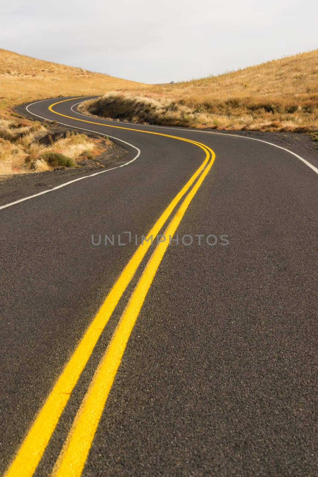 A well preserved two lane road leads around a bend to an interesting sky
