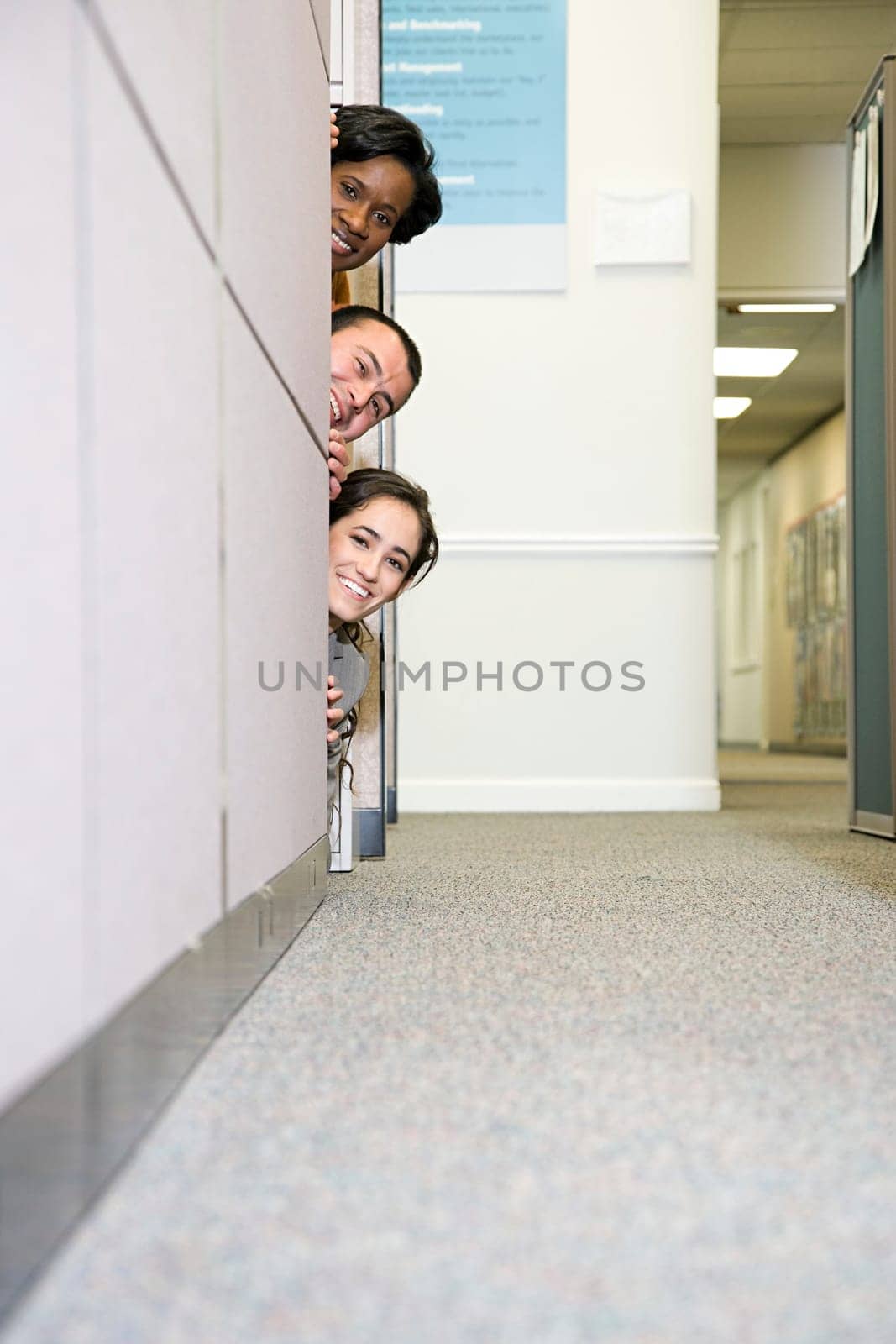 Colleagues peering around cubicle