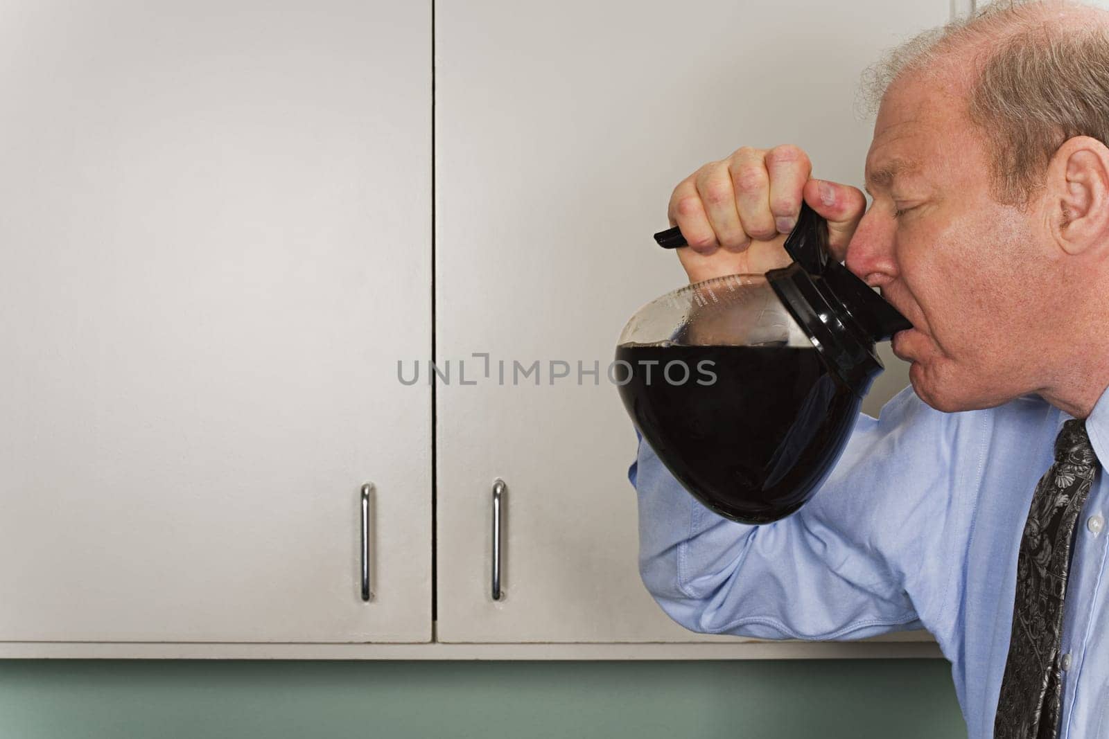 Businessman drinking out of coffee pot