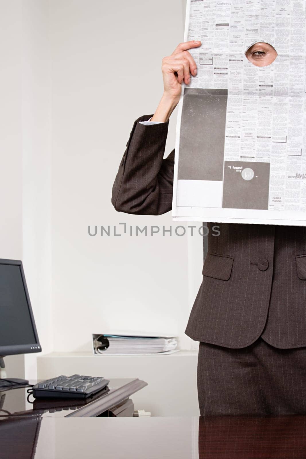 Woman looking through hole in newspaper
