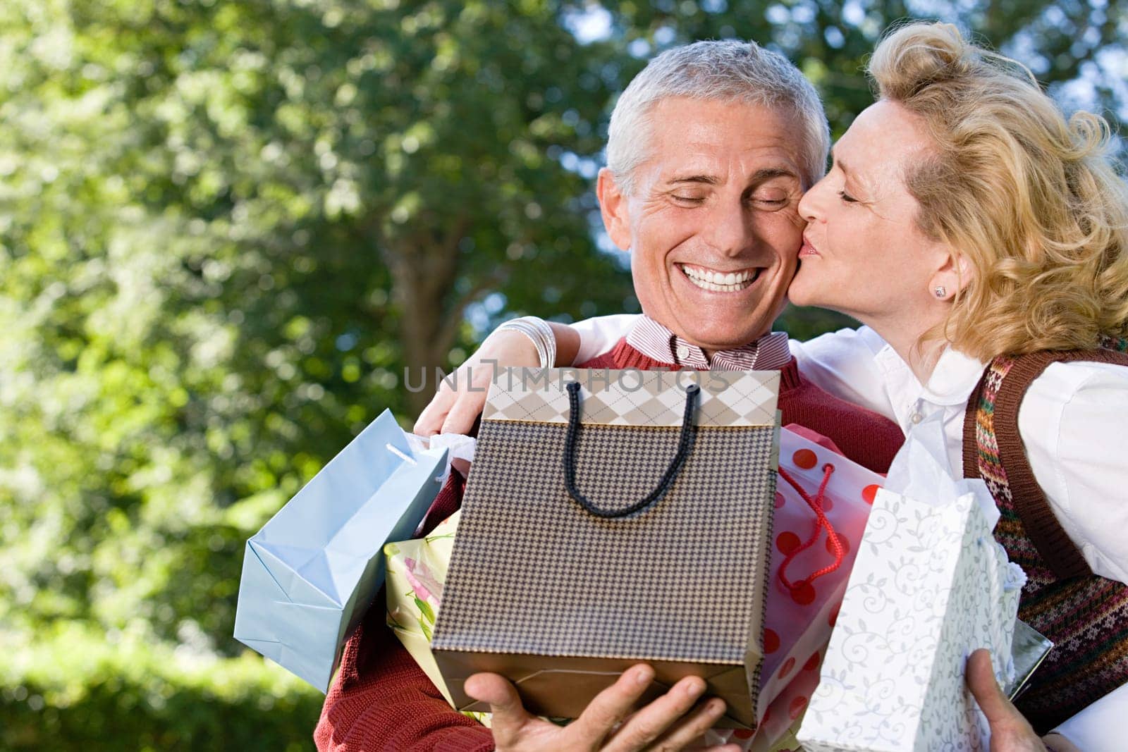 Wife kissing husband with bags of gifts