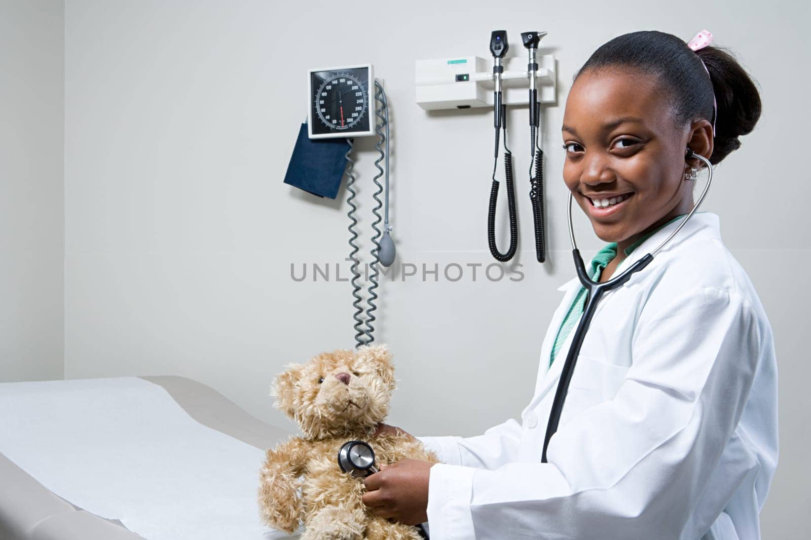 Girl doctor using stethoscope on teddy bear