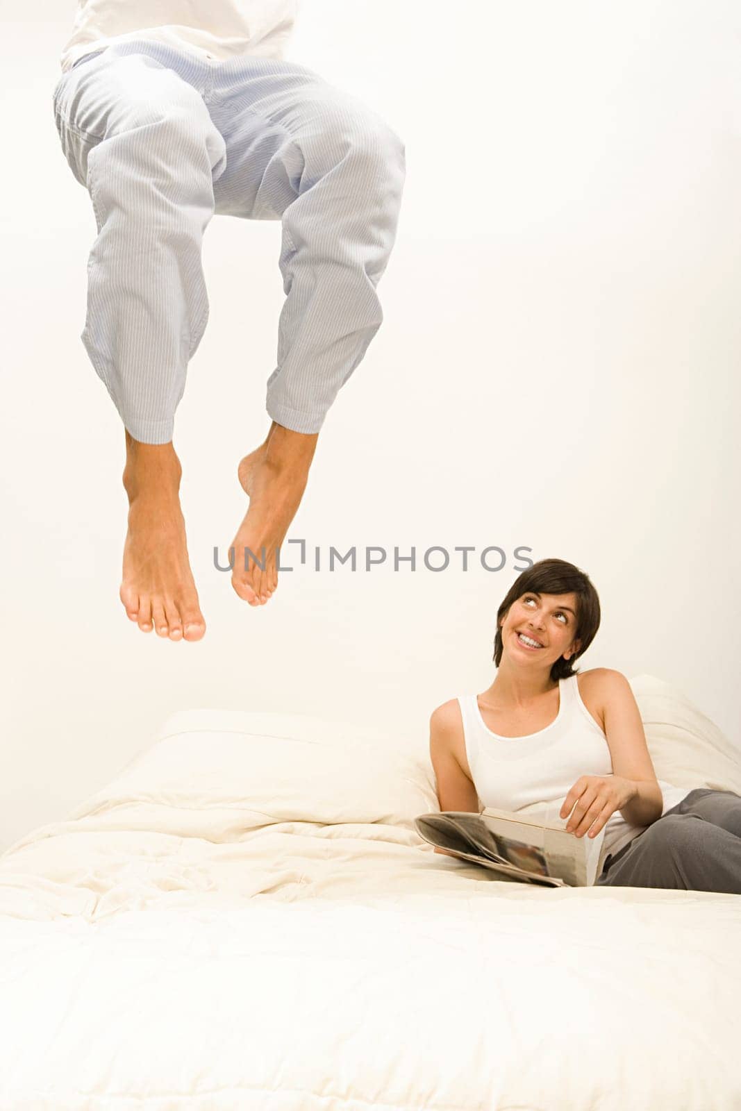 Woman watching husband jump on bed