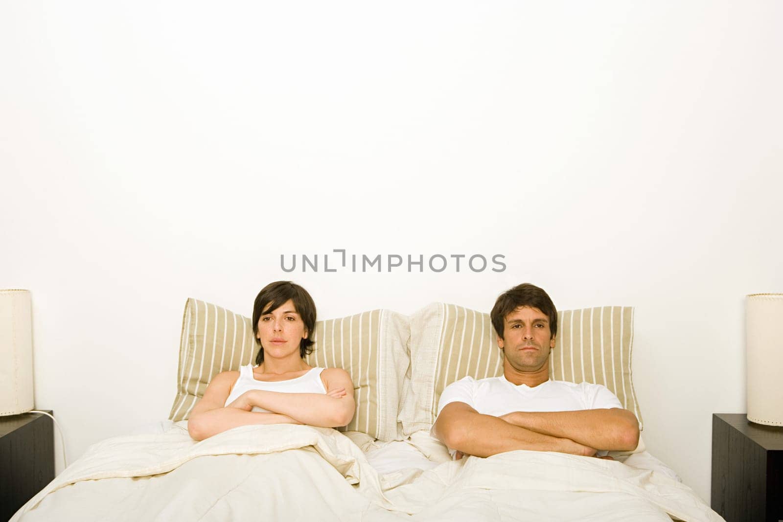 Couple in bed ignoring each other