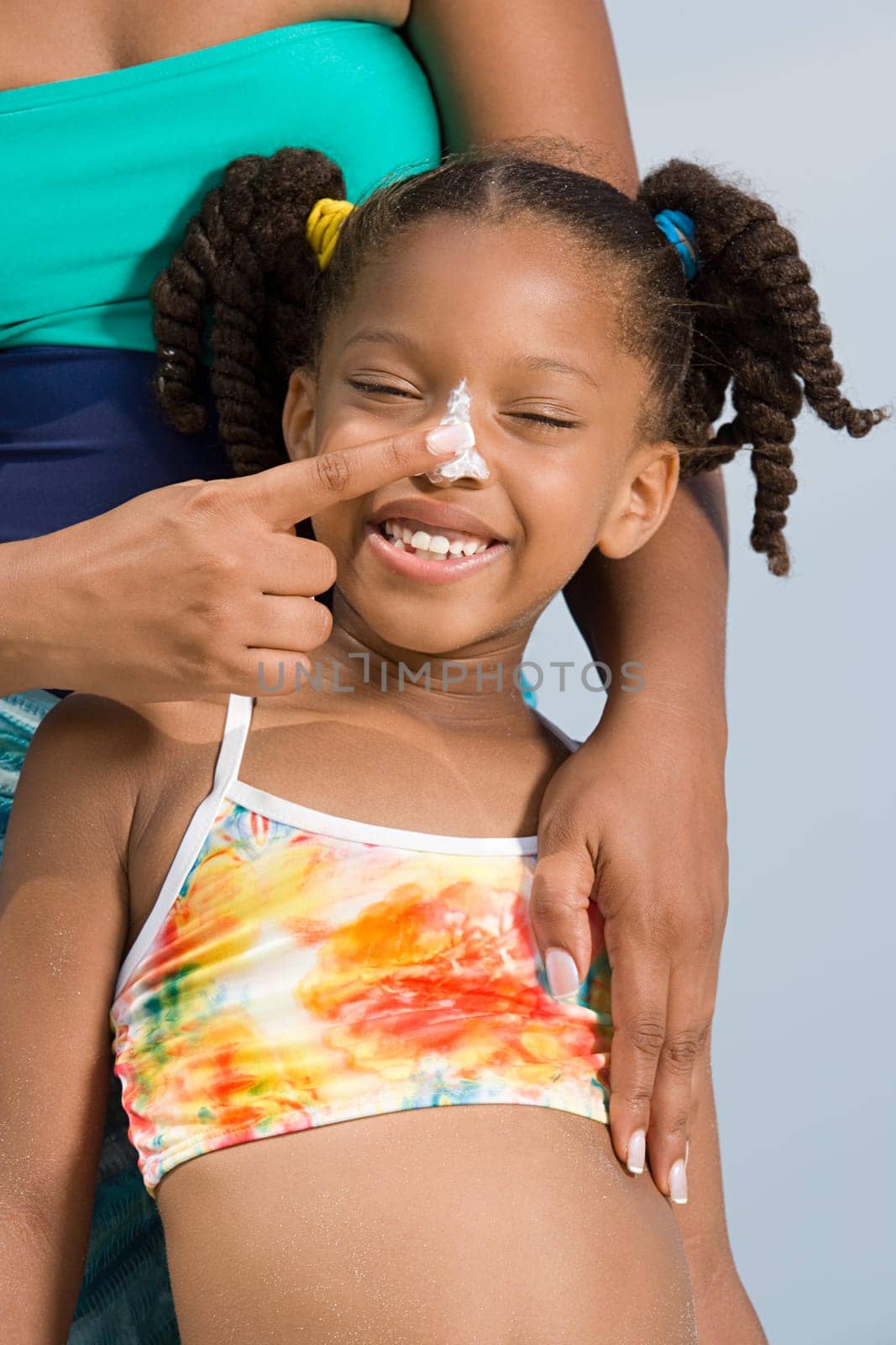 Mother putting suncream on daughters nose