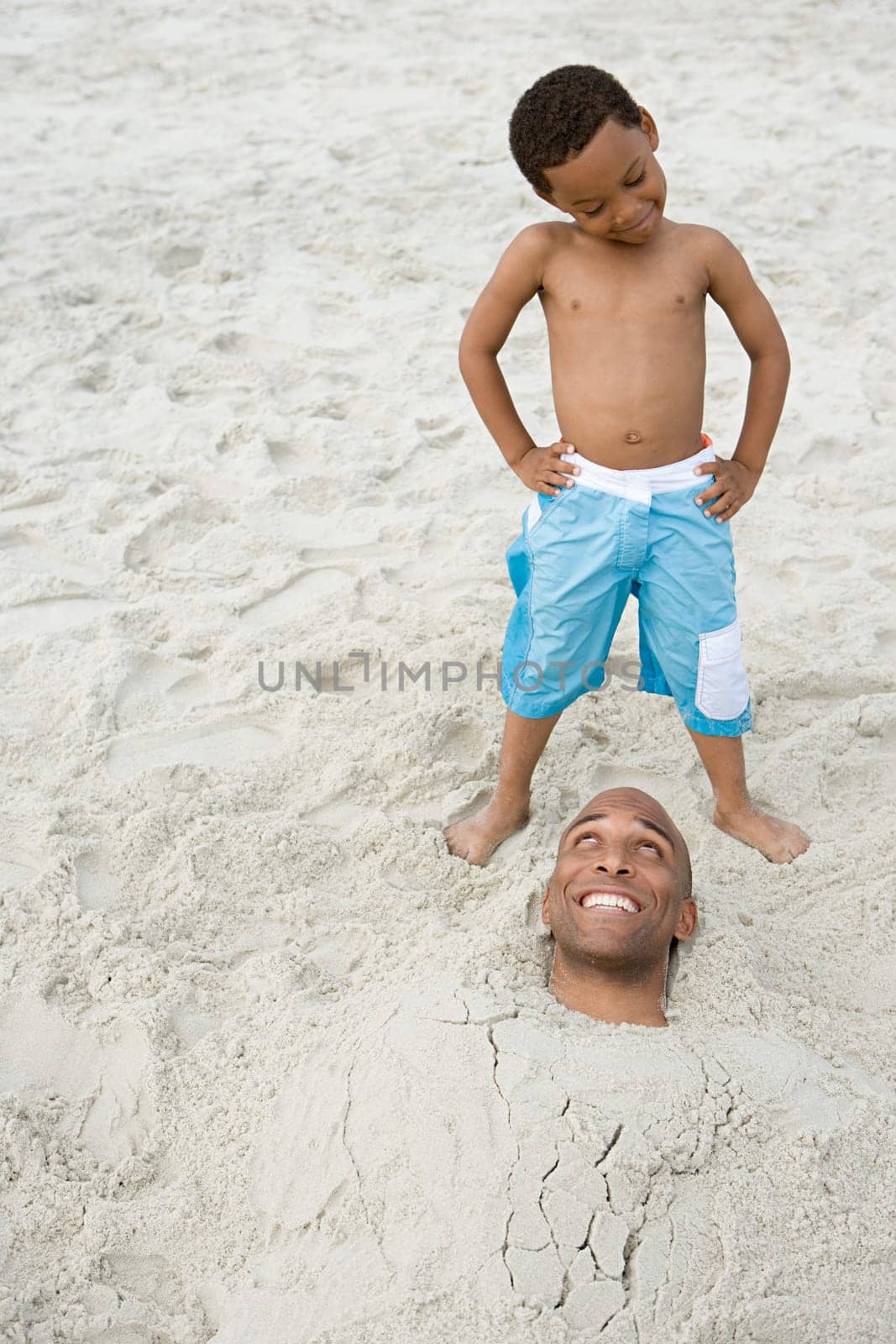 Son looking at father buried in sand