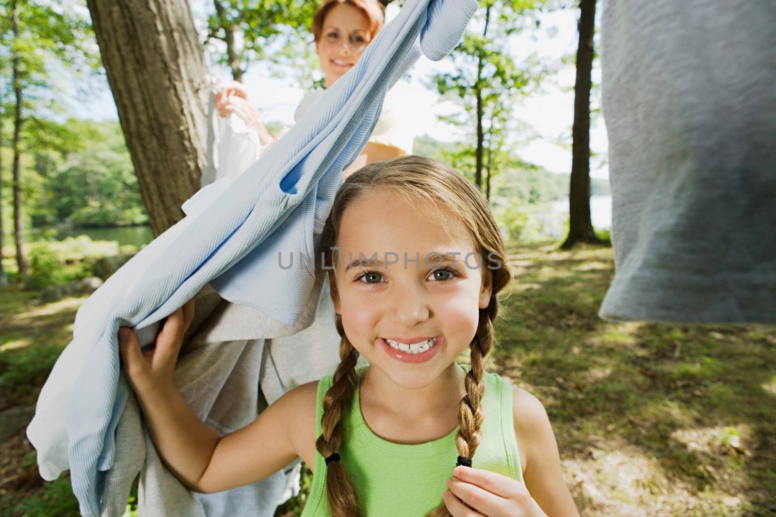Girl and mother hanging clothes in forest