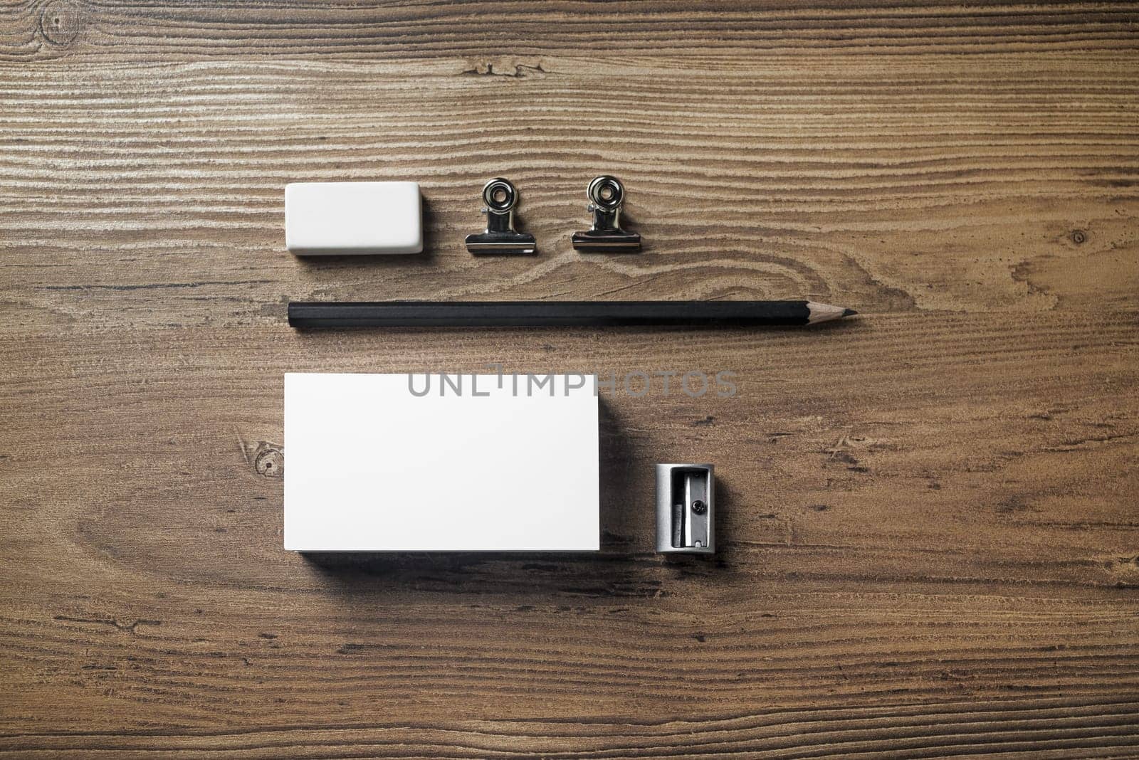 Photo of business card, pencil, eraser and sharpener on wood background. Blank stationery elements. Mock-up for branding identity. Studio shot. Top view.
