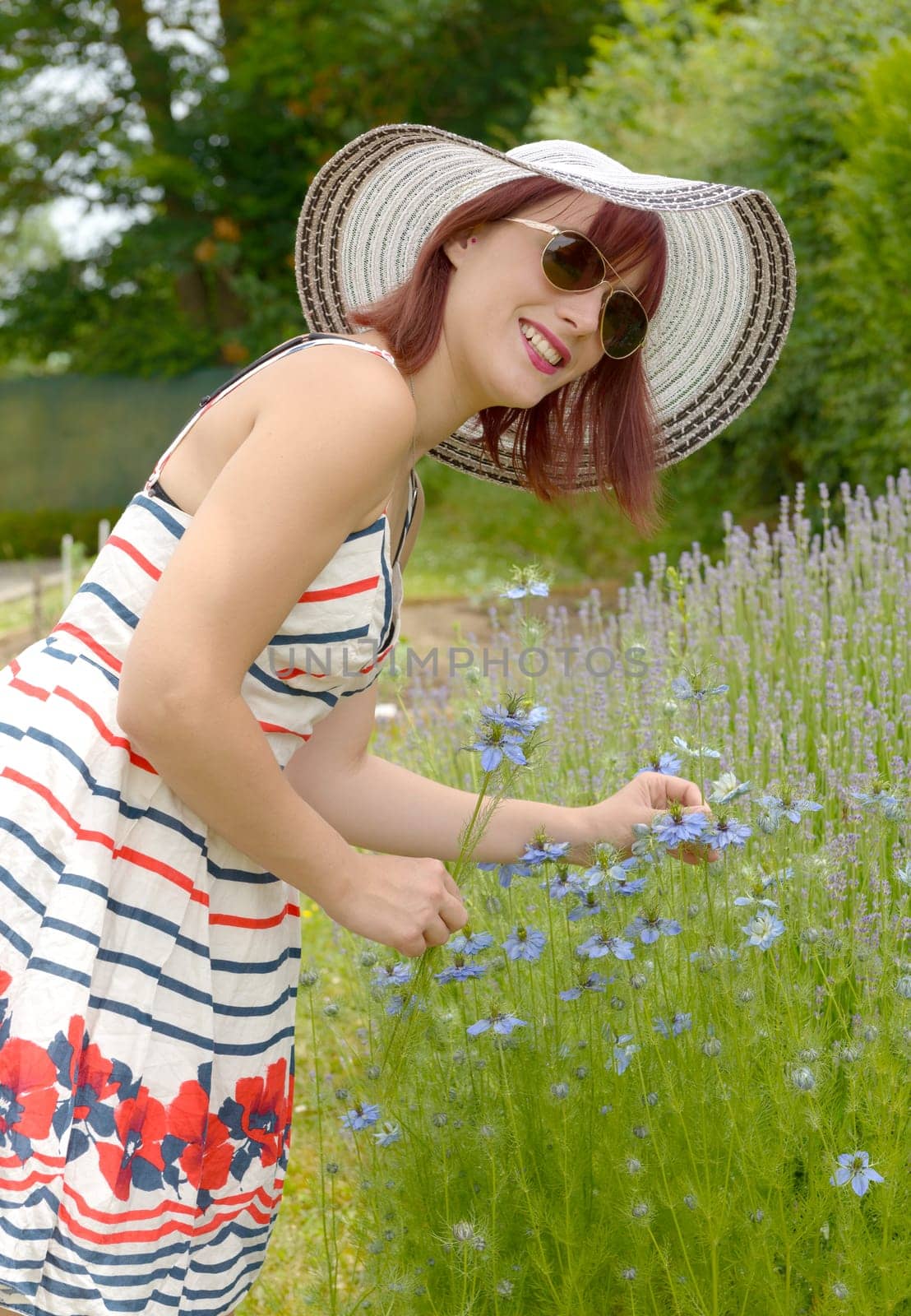 portrait of pretty girl wearing hat, dress and sunglasses. She smiling to the camera.