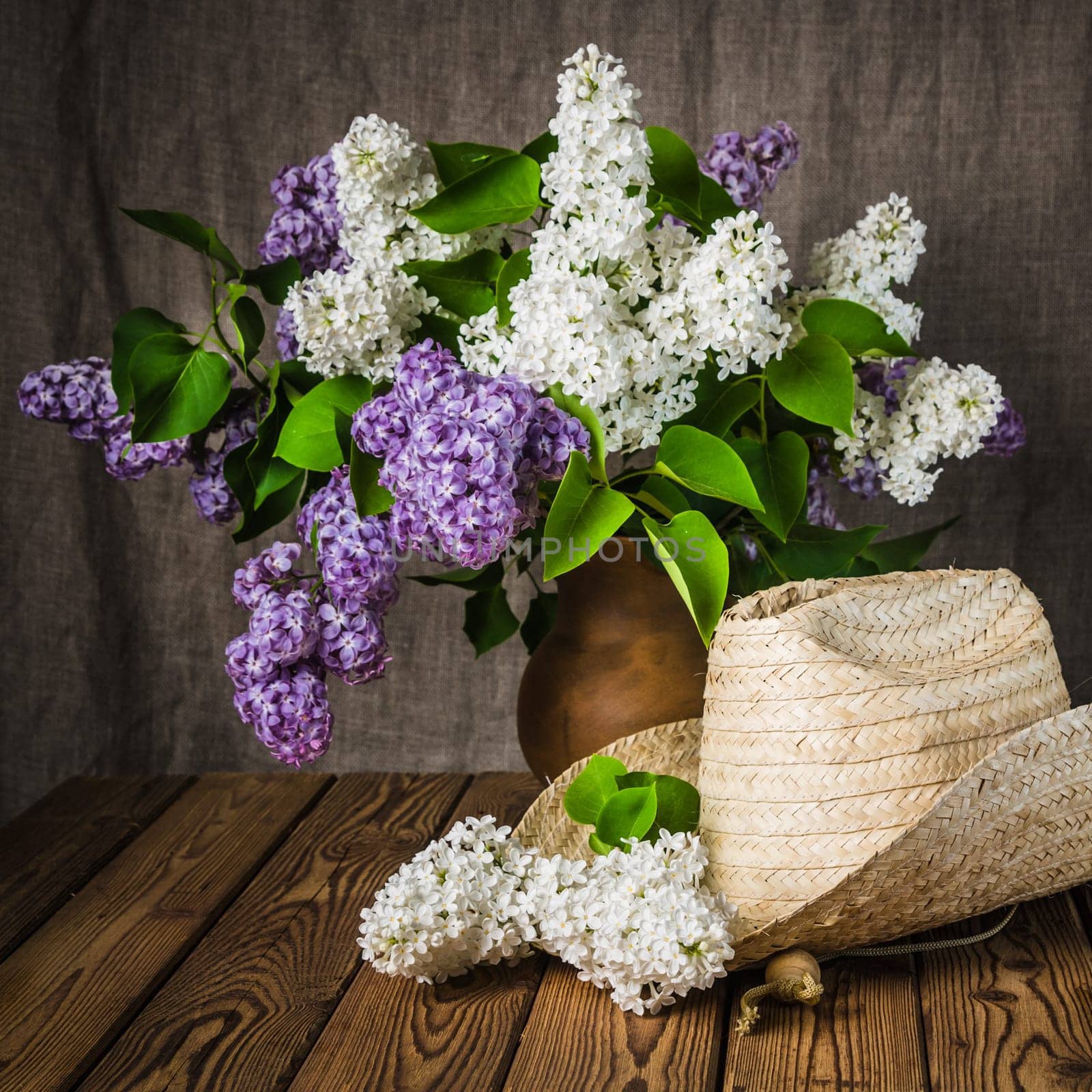 Still-life with a bouquet of lilacs and a straw hat, close-up