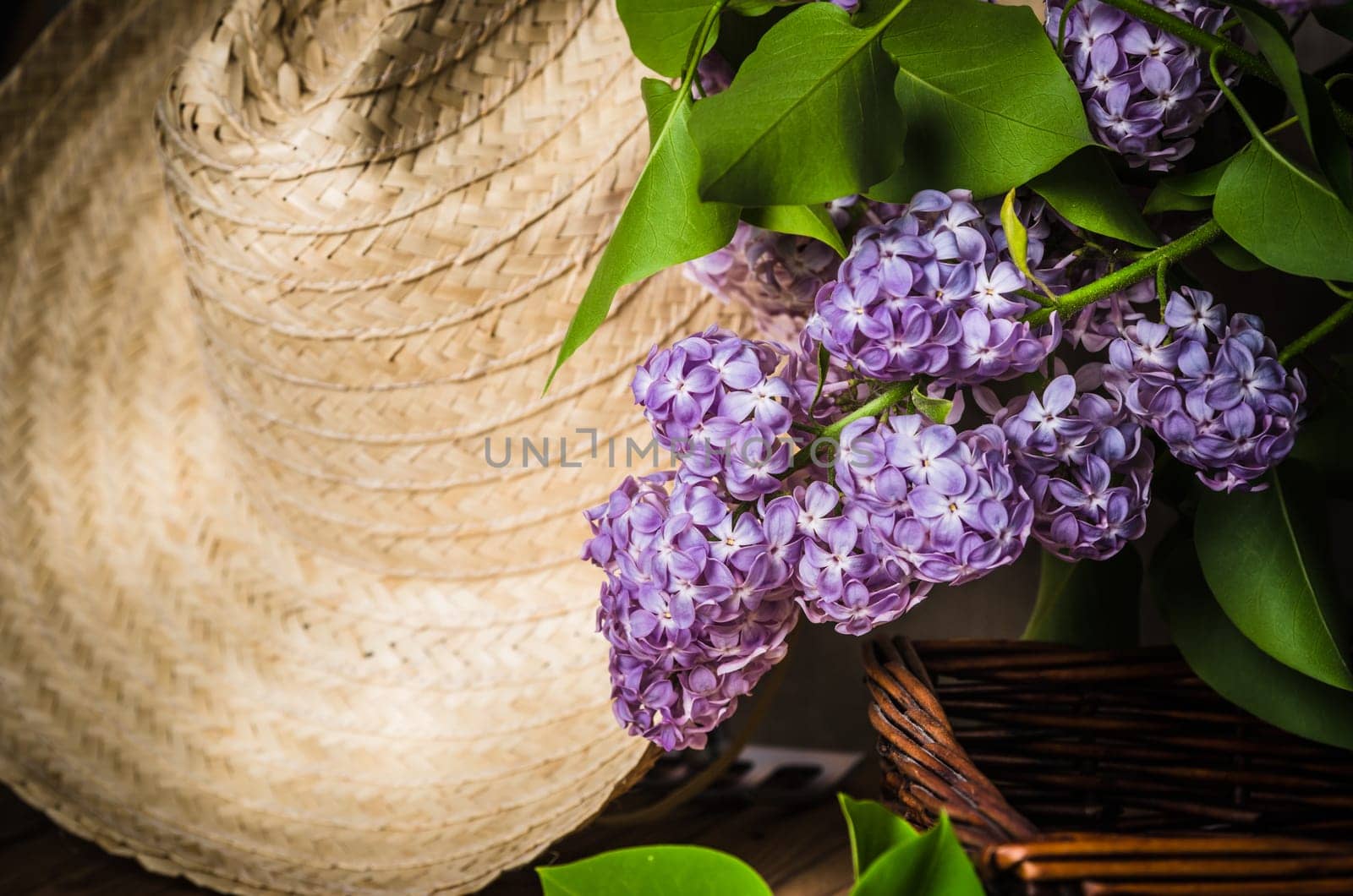 Still-life with a bouquet of lilacs and a straw hat, close-up