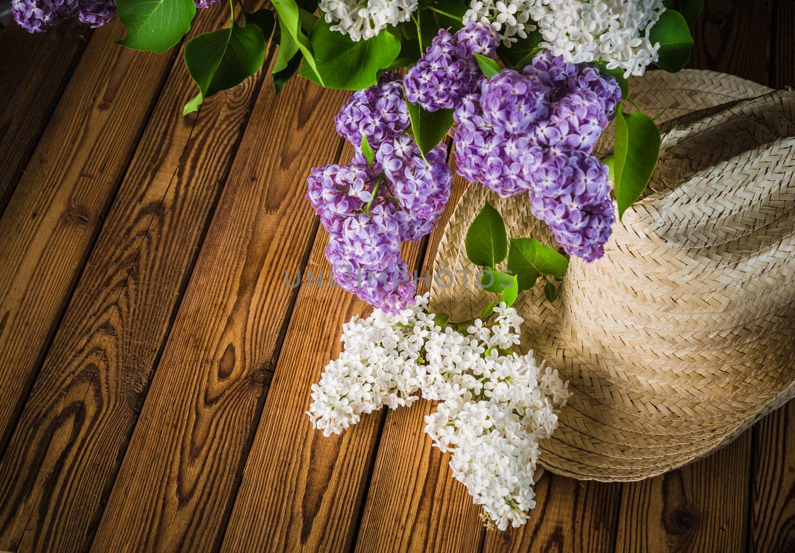Still-life with a bouquet of lilacs and a straw hat, close-up
