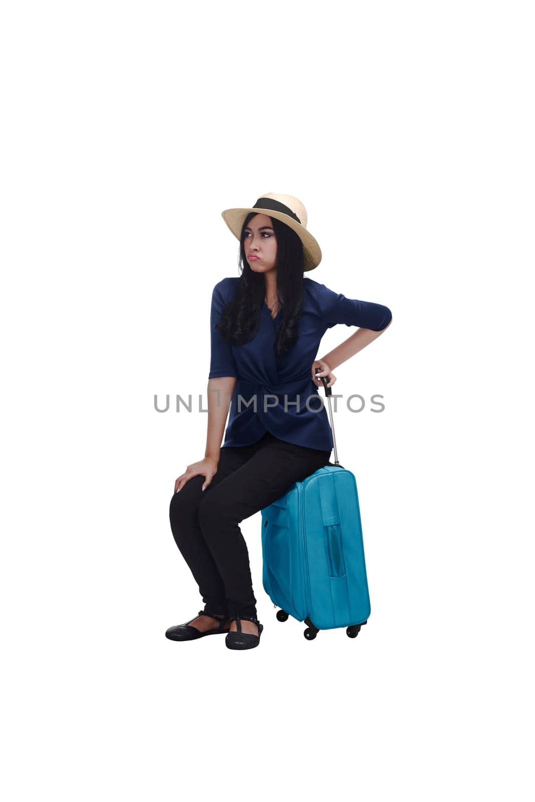 Tired young asian traveler woman sitting on suitcase isolated over white background