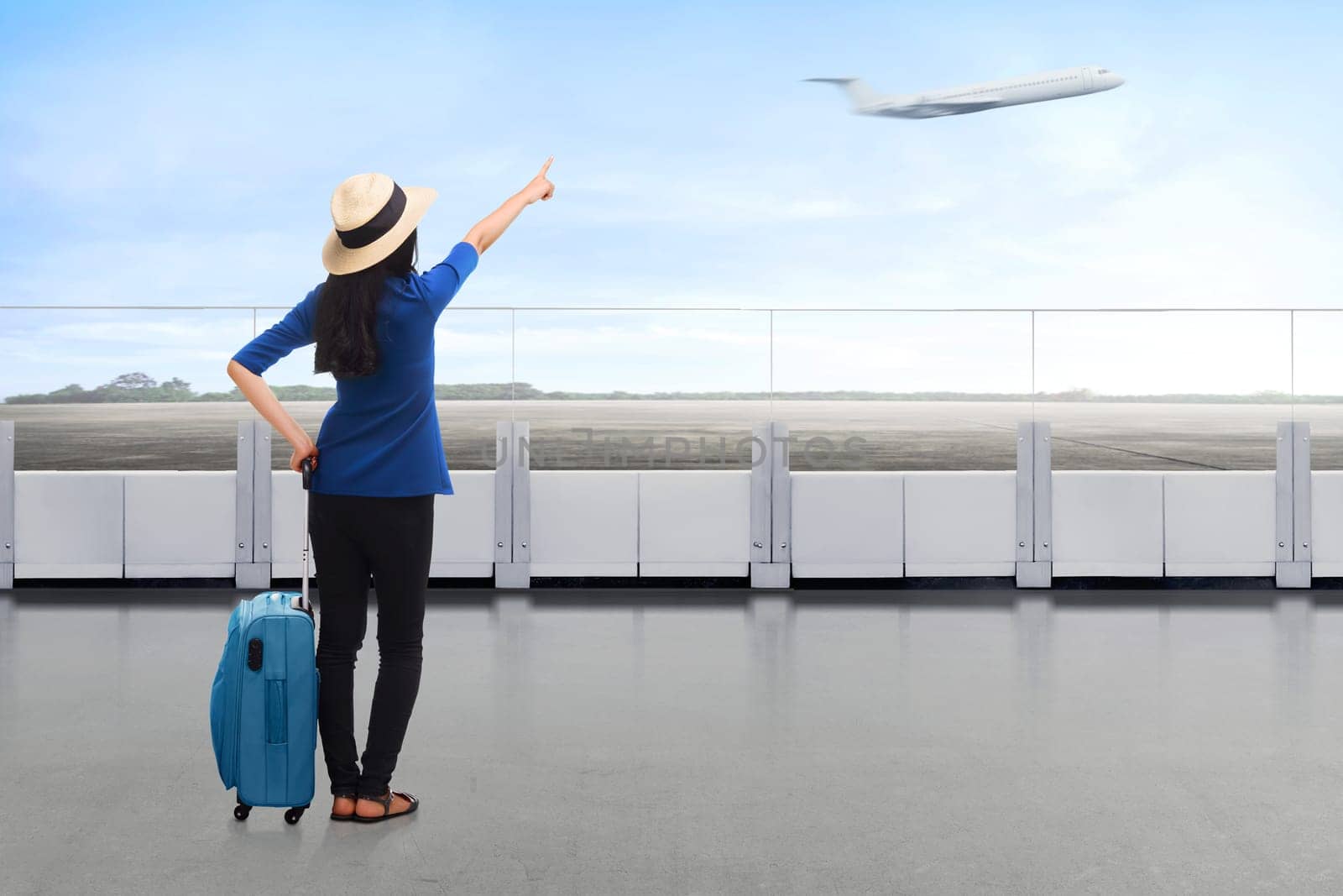 Traveler asian woman carrying suitcase looking airplane at the airport terrace