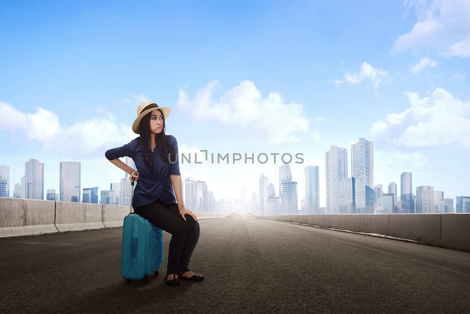 Tired asian traveler woman sitting on luggage waiting flight at terminal airport