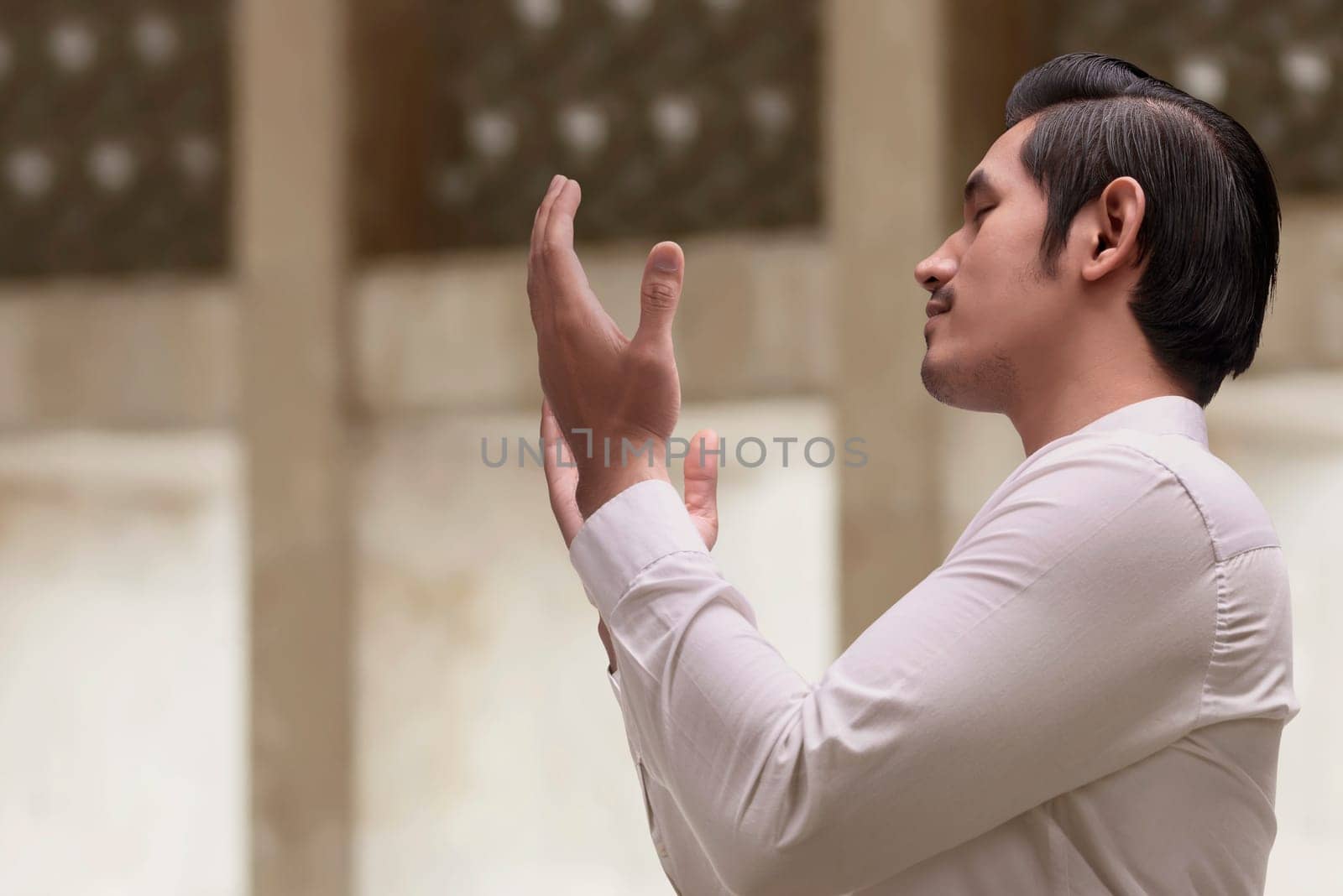 Religious asian muslim man in traditional dress praying in the mosque